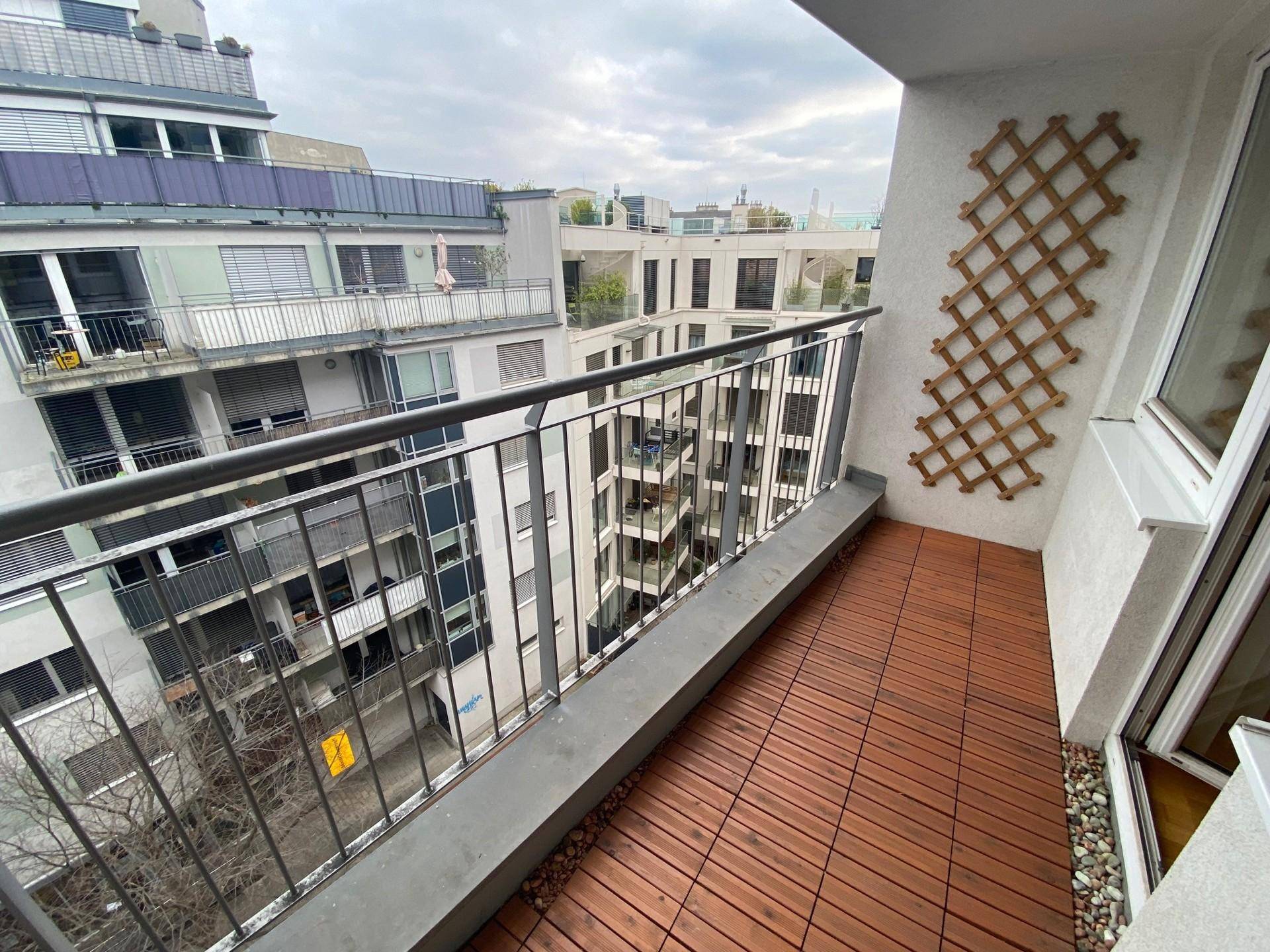 Balkon mit Holzboden und Blick auf die umliegenden Gebäude.