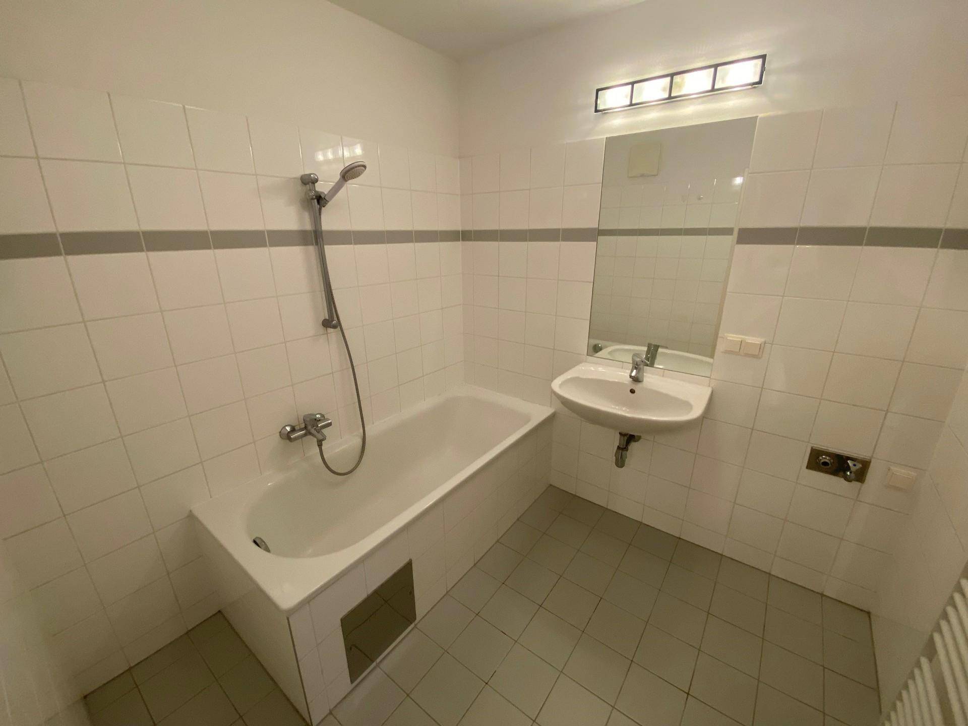 Badezimmer mit Badewanne, Dusche und Waschbecken in schlichtem Design.