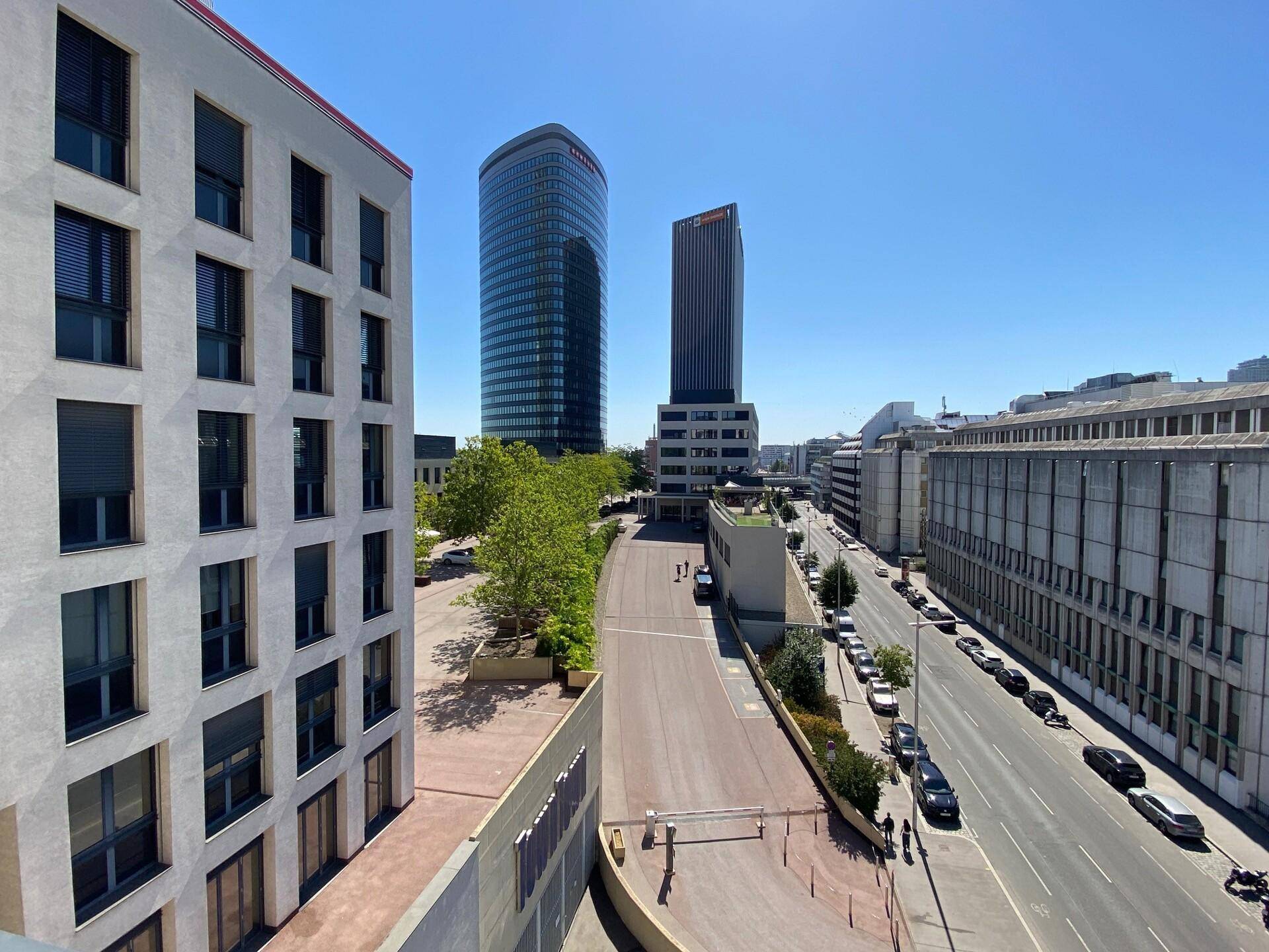 Panoramablick auf die Stadt mit modernen Hochhäusern und einer belebten Straße unter blauem Himmel.