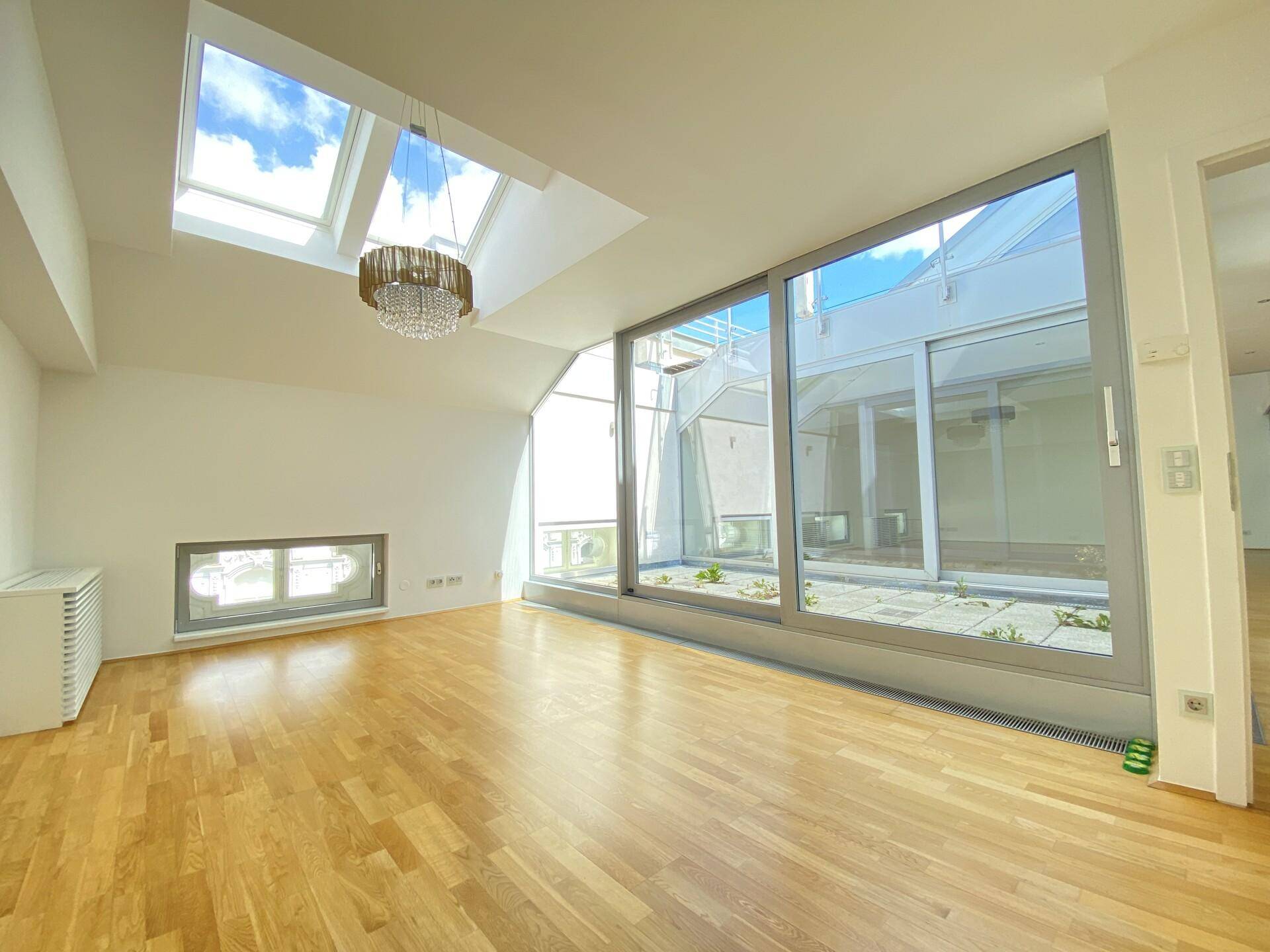 Helles Wohnzimmer mit Parkettboden, großen Fenstern und Oberlichtern für viel Tageslicht.