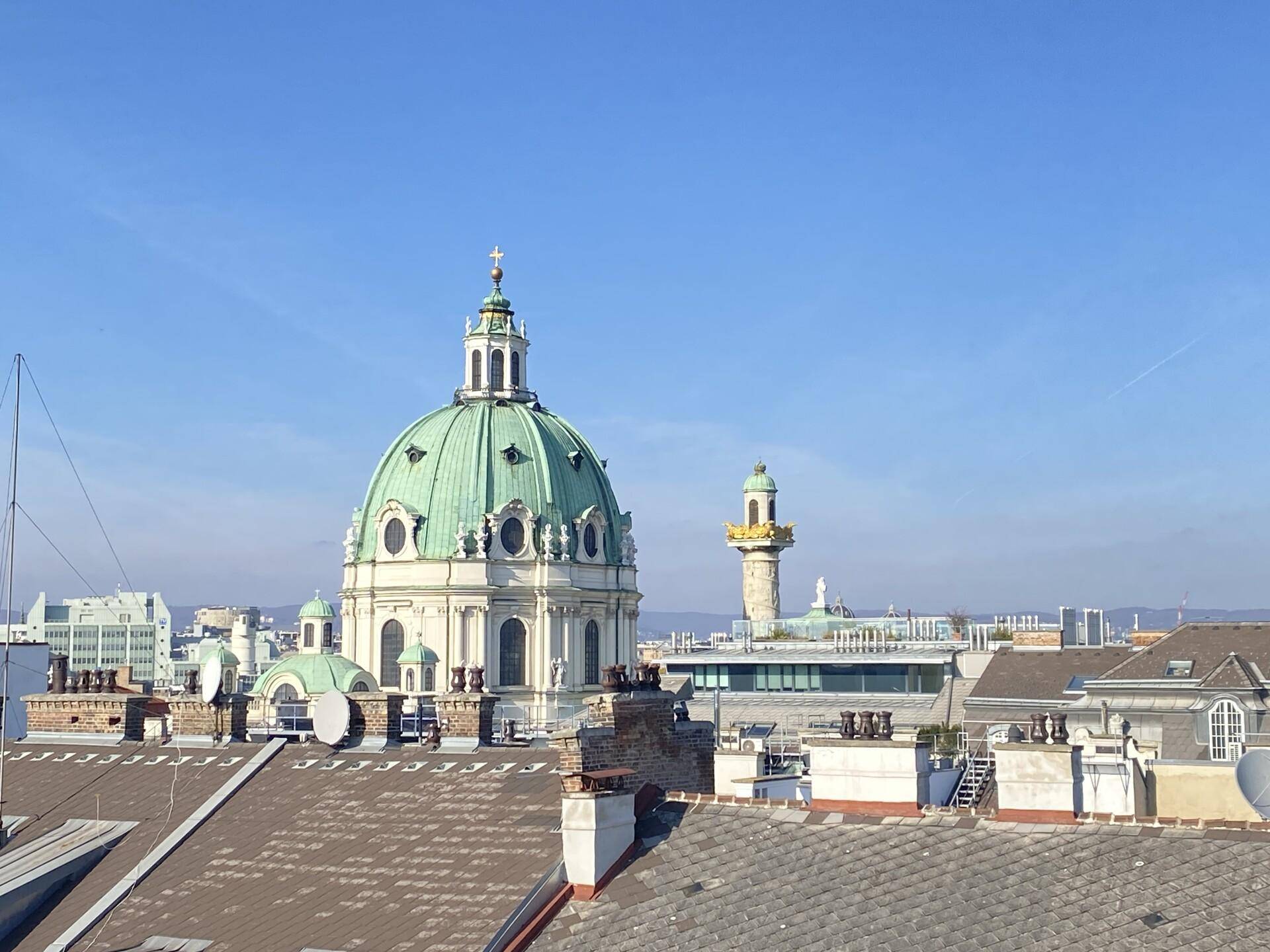 Panoramablick über die Dächer der Stadt mit historischer Kuppelkirche unter blauem Himmel.