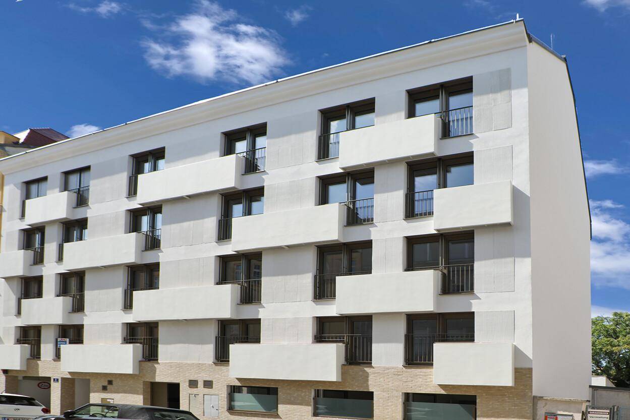 Ansicht der modernen Wohnhausfassade mit symmetrisch angeordneten Balkonen und Fenstern.