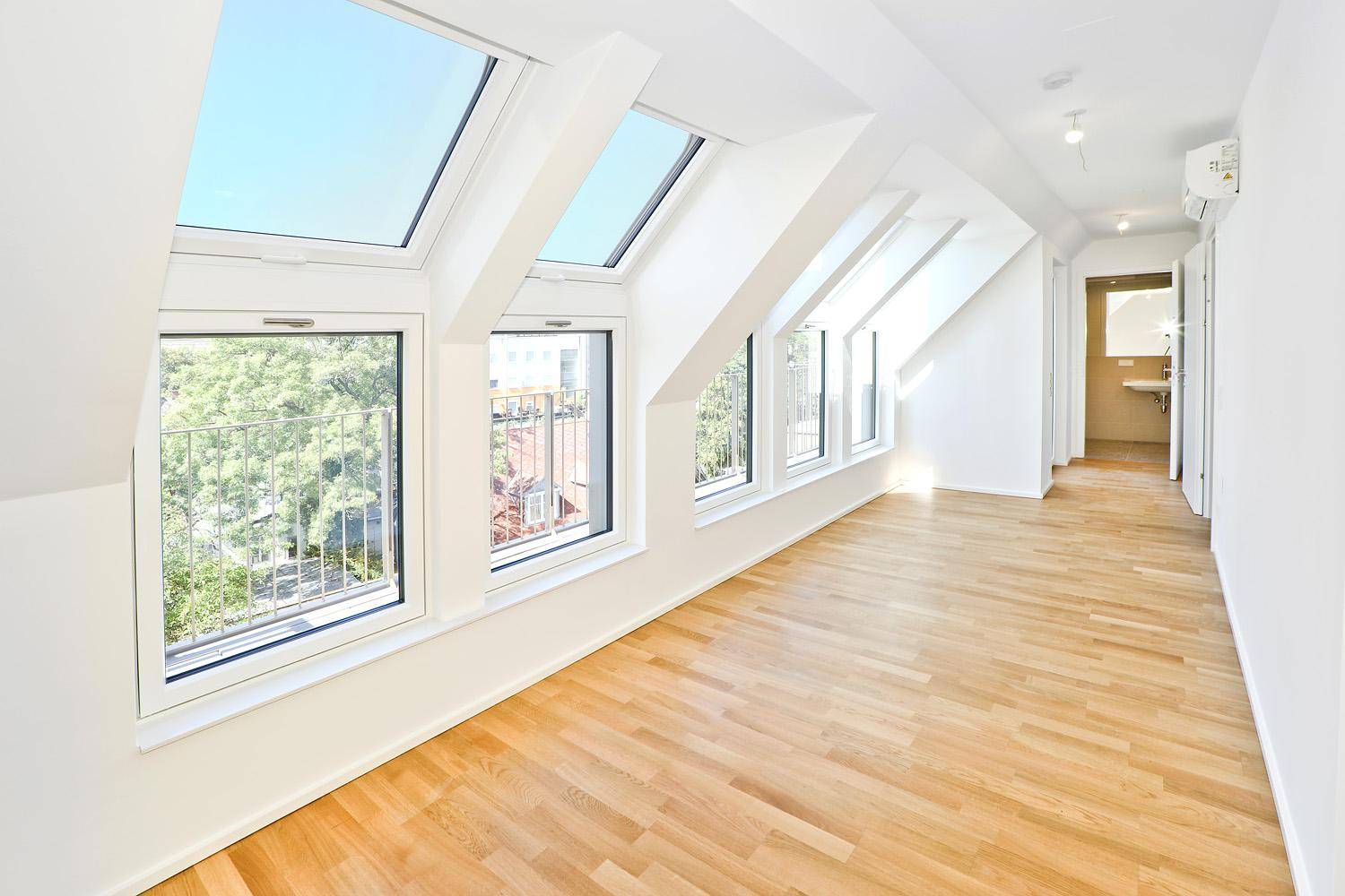 Großzügiger Wohnbereich im Dachgeschoss mit Parkettboden, Klimaanlage und französischem Balkon.