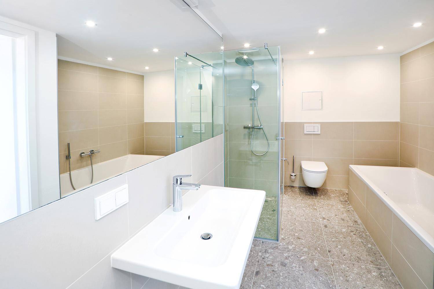 Modernes Badezimmer mit Badewanne, Duschkabine, Wand-WC und großem Spiegel.