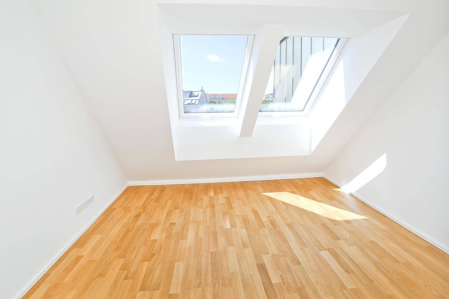 Ruhiges Schlafzimmer im Dachgeschoss mit Parkettboden und zwei großen Dachfenstern.