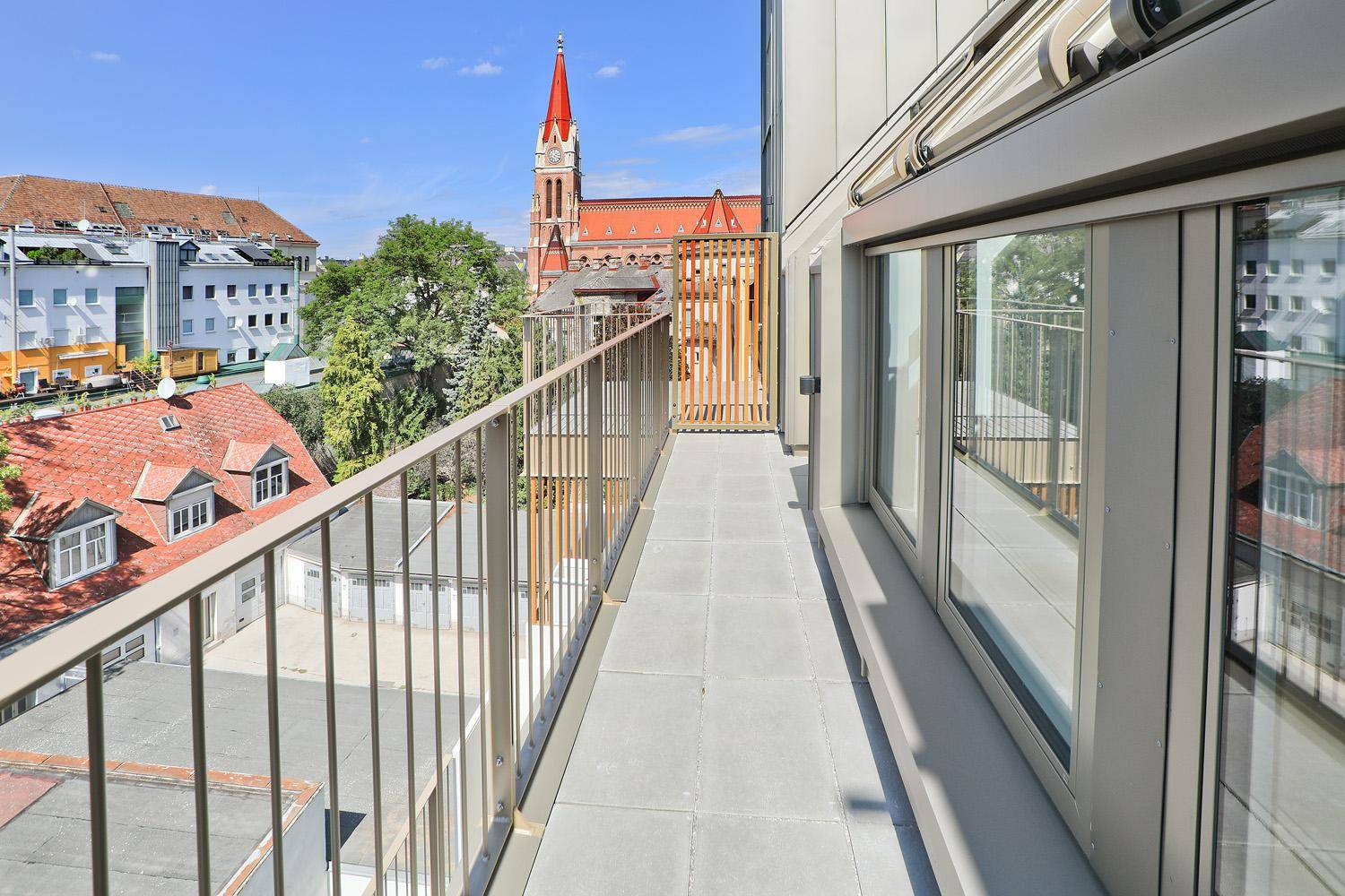 Langer Balkon mit Fliesenboden und malerischem Blick auf eine Kirche und die Stadt.