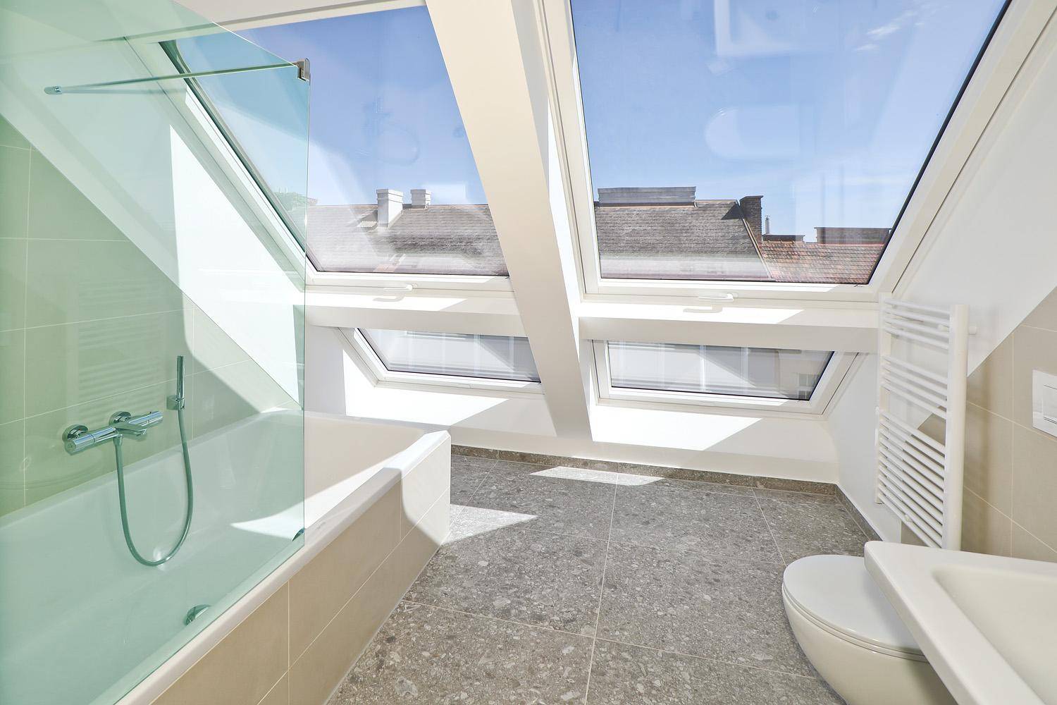 Helles Badezimmer im Dachgeschoss mit Badewanne, WC, Handtuchheizkörper und Dachfenstern.