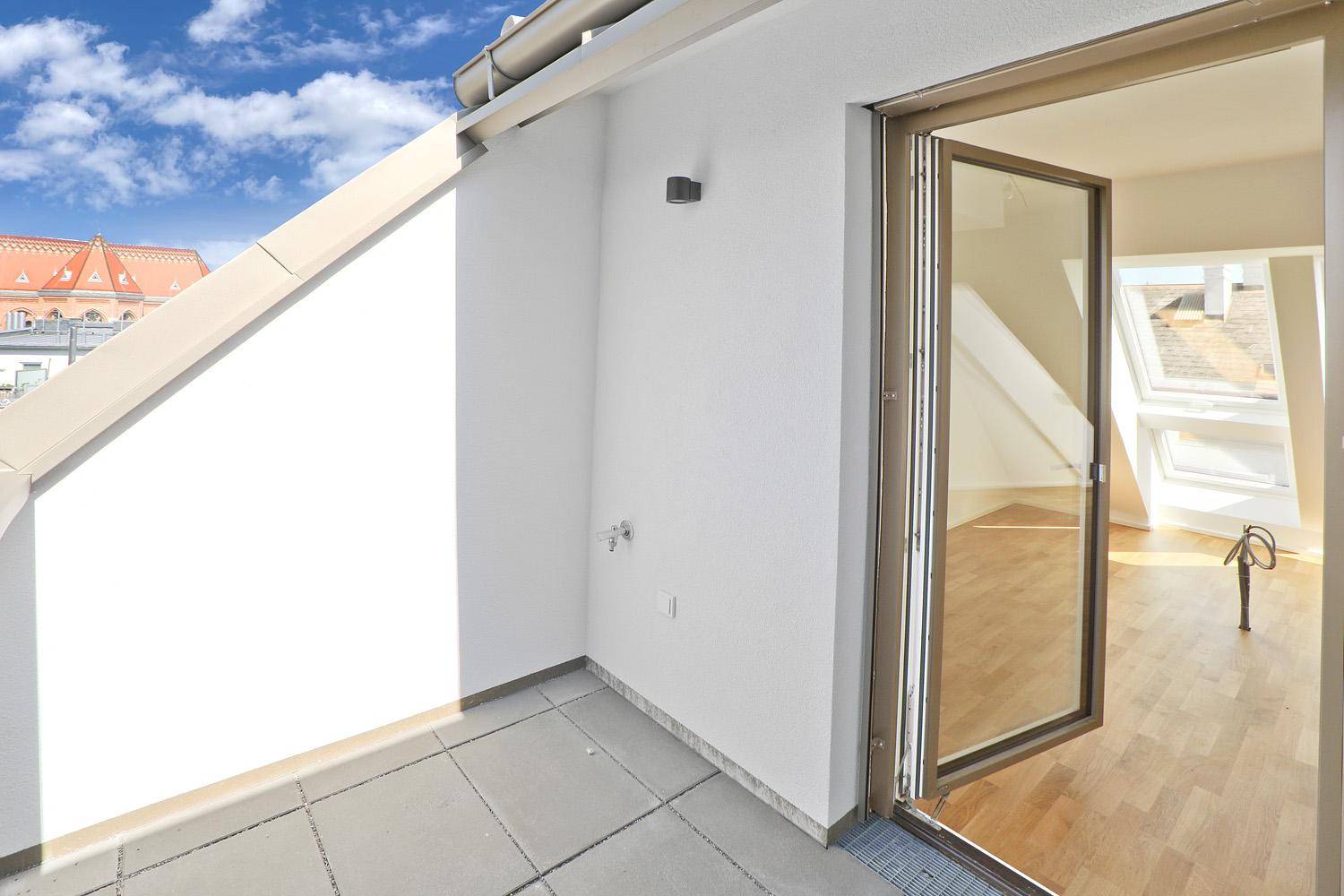 Kleiner Balkon mit Fliesenboden und Zugang zu einem hellen Innenraum im Dachgeschoss.