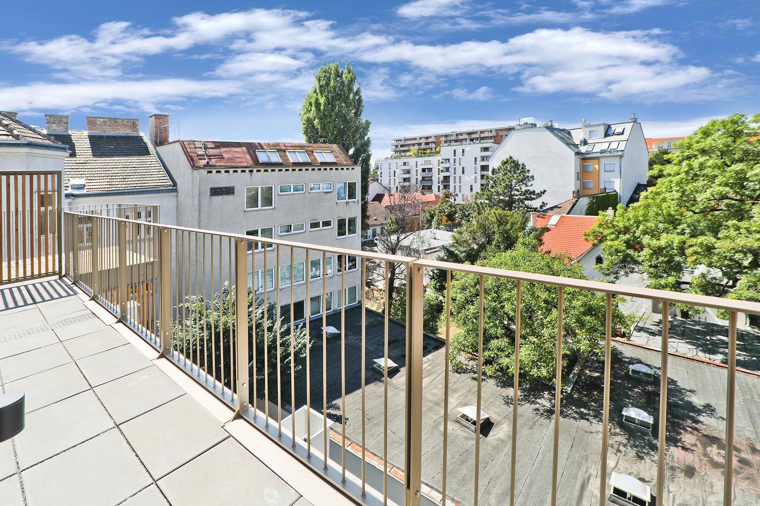 Geräumige Terrasse mit Fliesenboden und weitem Blick über die Stadt und umliegende Gebäude.