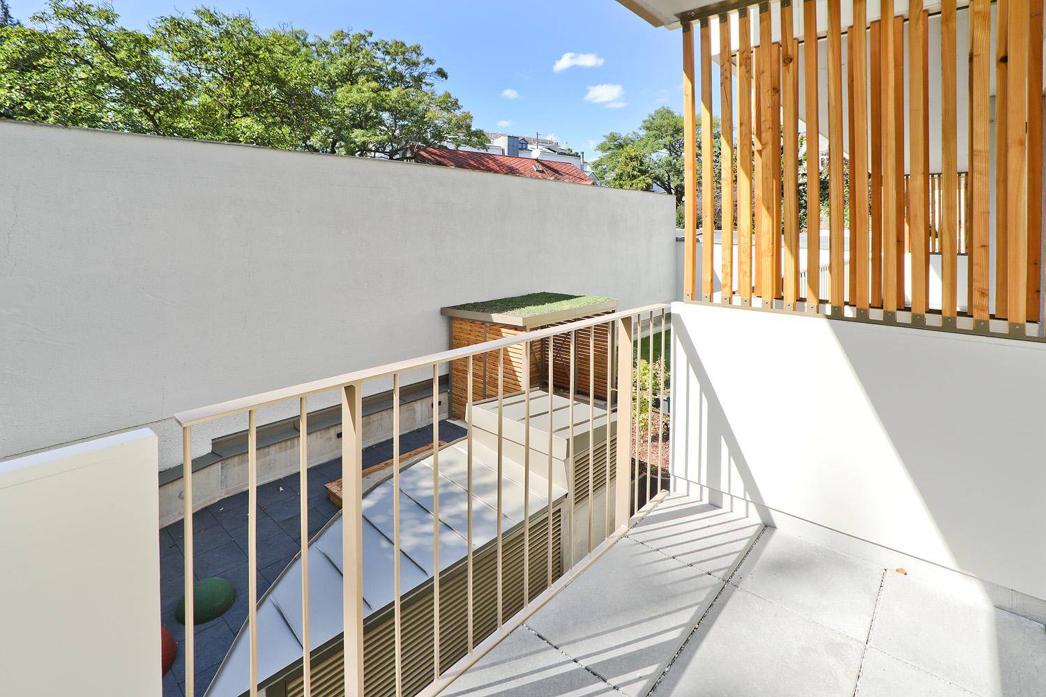 Moderner Balkon mit Holzelementen und Blick auf begrünte Dächer und Umgebung.