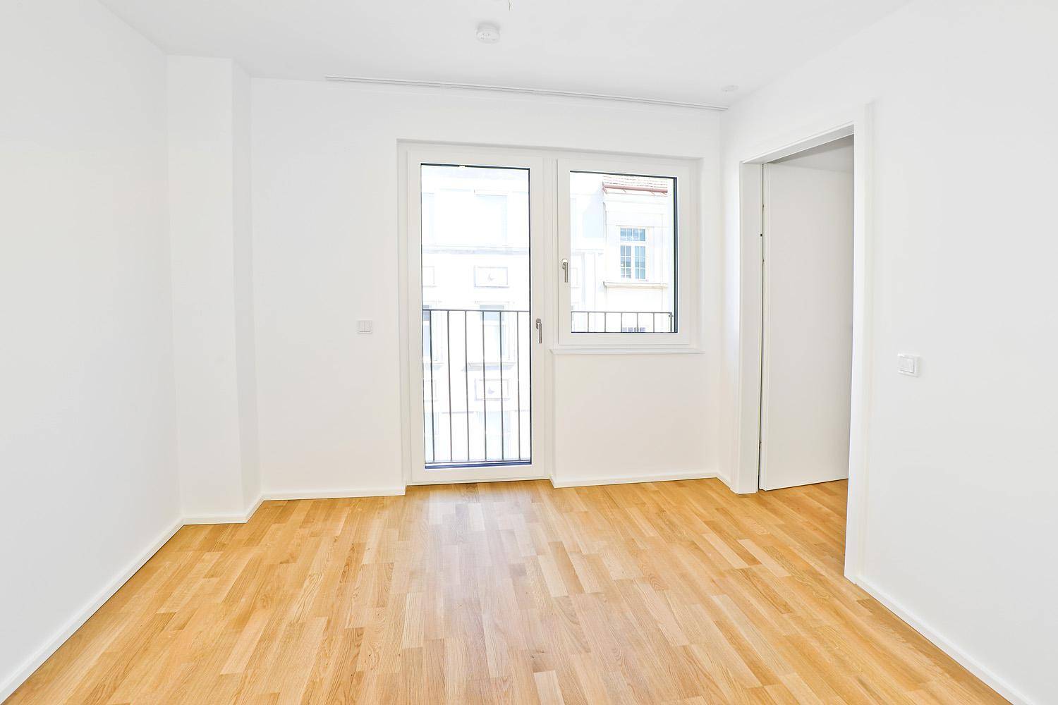 Helles Schlafzimmer mit Parkettboden und französischem Balkon.