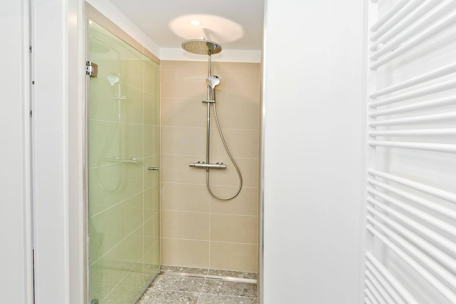 Modernes Badezimmer mit Duschkabine, Regendusche und Handtuchheizkörper.