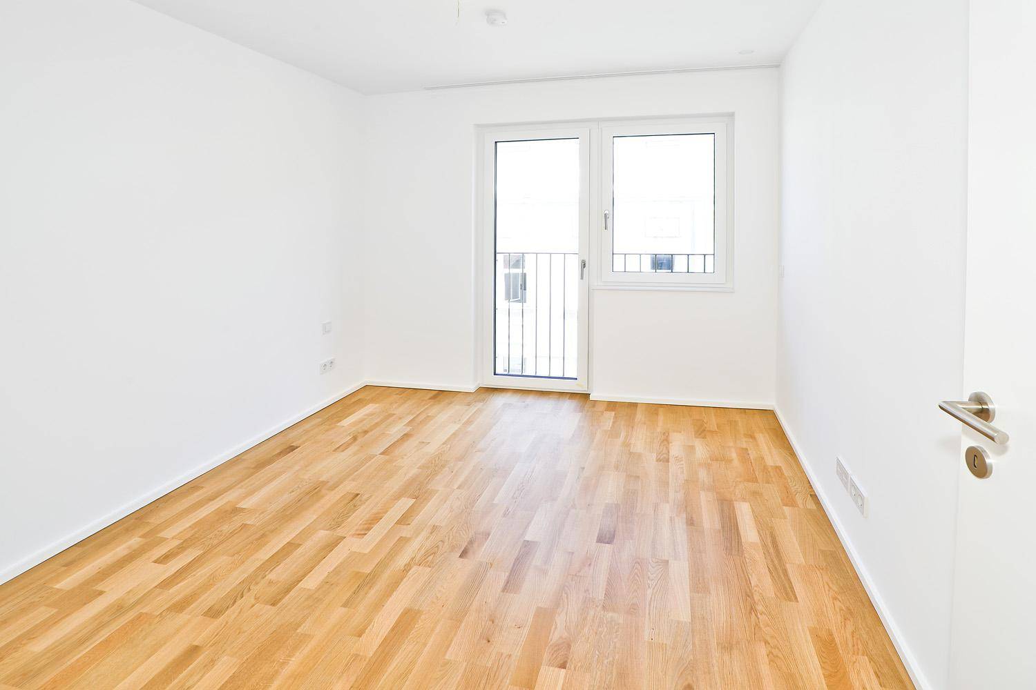 Lichtdurchflutetes Schlafzimmer mit Parkettboden und Zugang zum französischen Balkon.