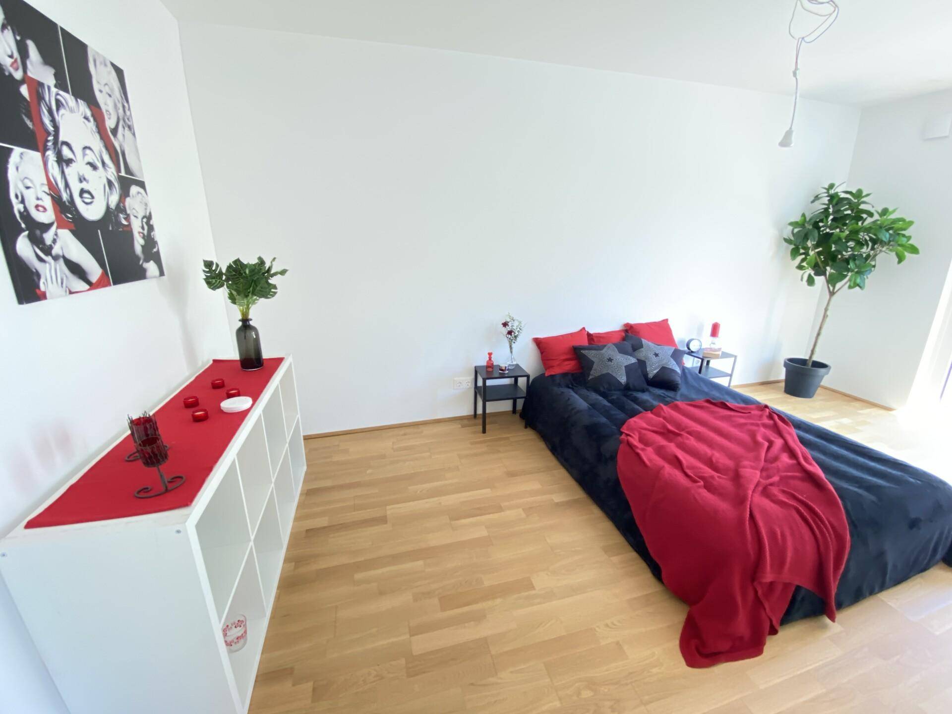 Schlafzimmer mit Holzboden, einem Bett auf dem Boden und minimalistischer Einrichtung.