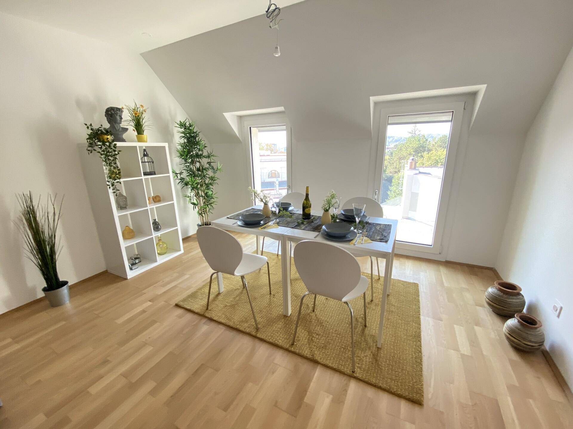 Heller Essbereich mit Holzboden, modernem Tisch und Stühlen unter schrägen Dachfenstern.