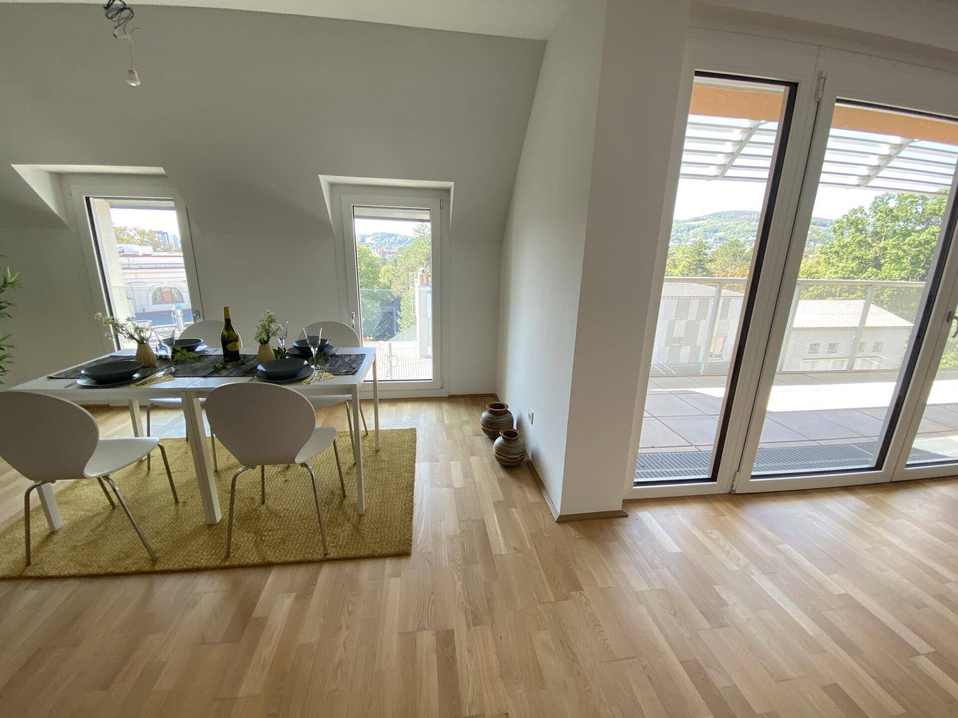 Essbereich mit Holzboden, modernem Esstisch und Zugang zu einer sonnigen Terrasse mit Weitblick.