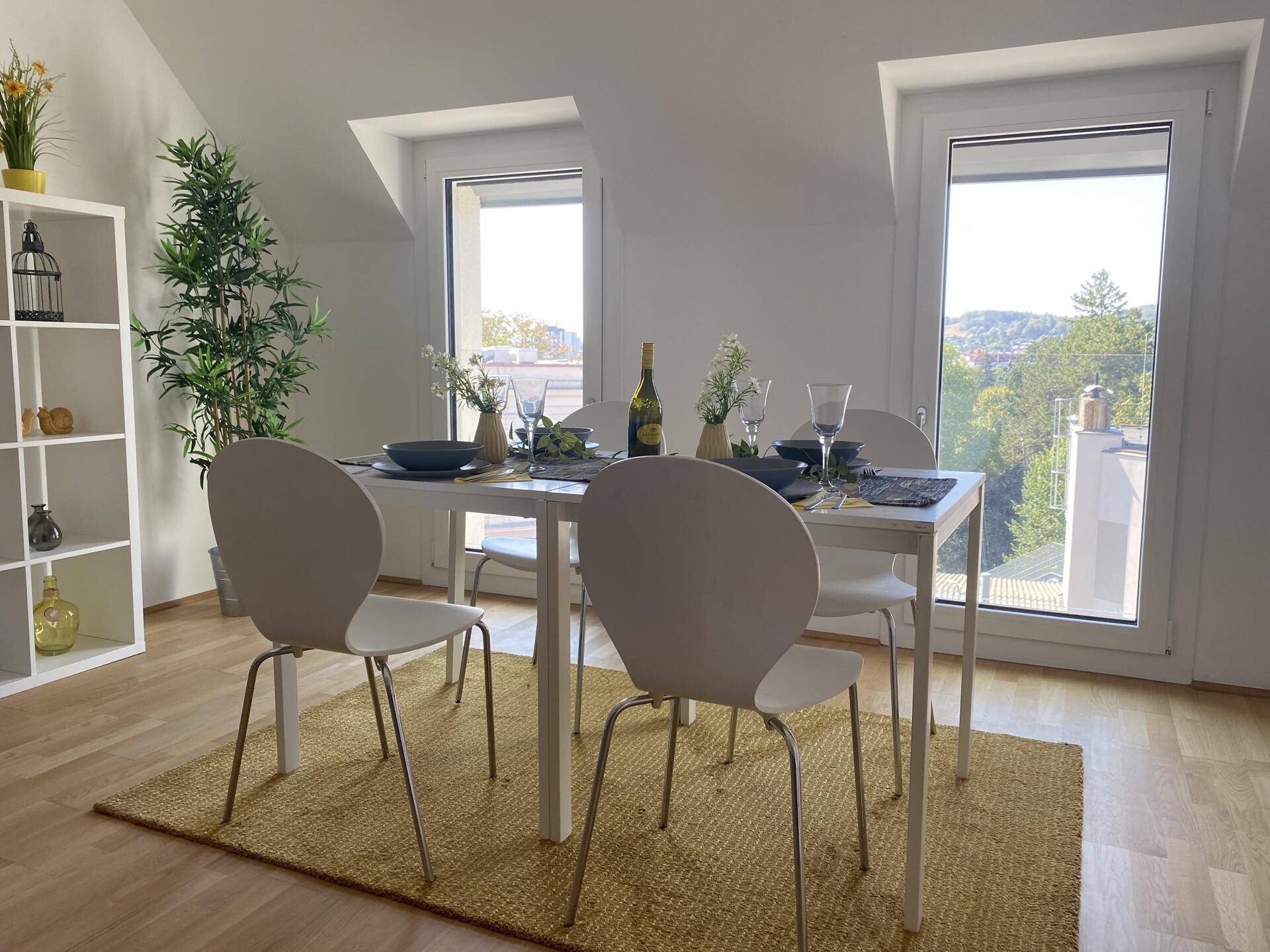 Essbereich mit modernem Tisch, Stühlen und Holzboden, hell beleuchtet durch Dachfenster.