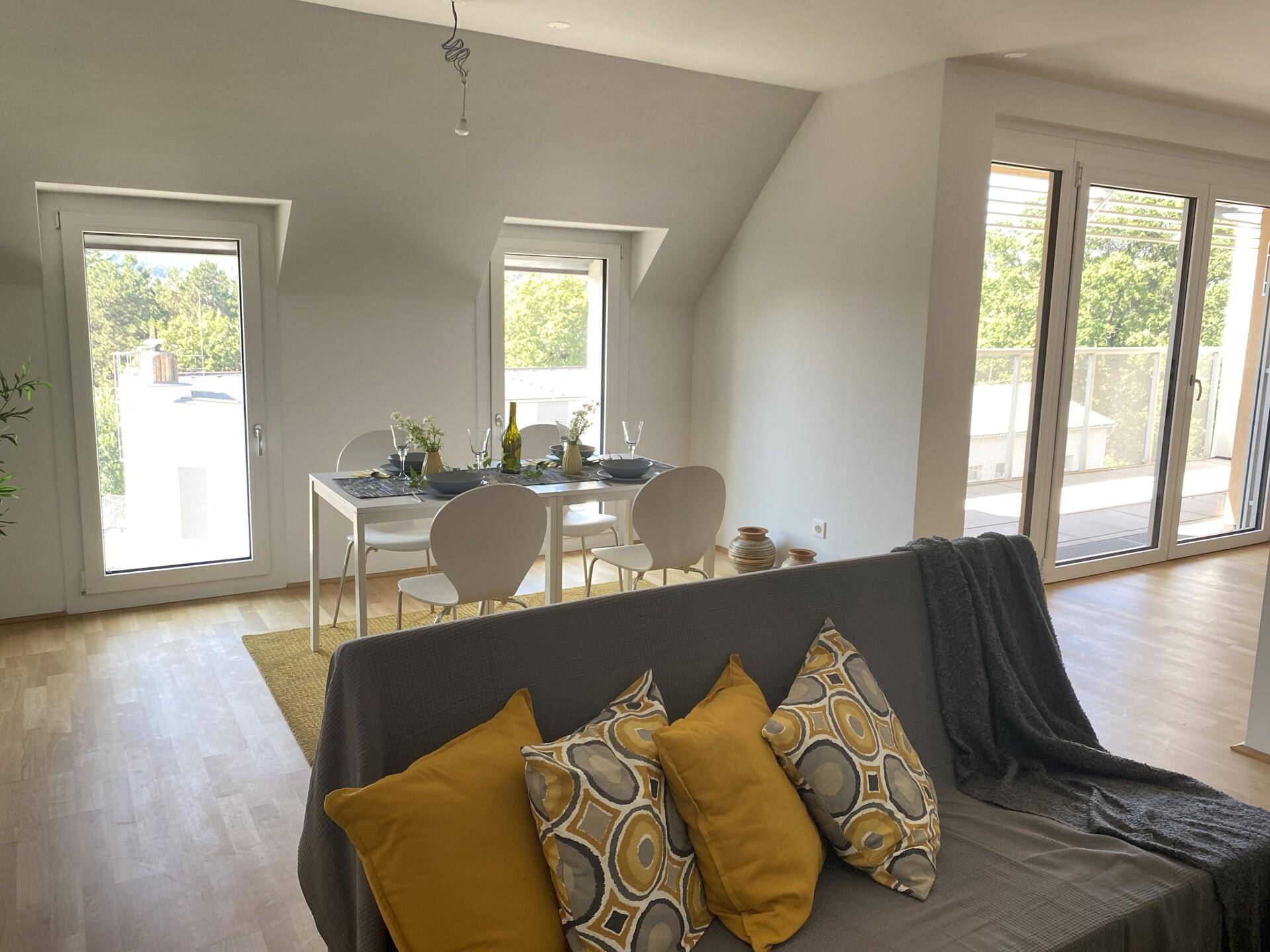 Gemütlicher Wohnbereich mit Sofa und Blick auf den Essbereich sowie die Außenterrasse.