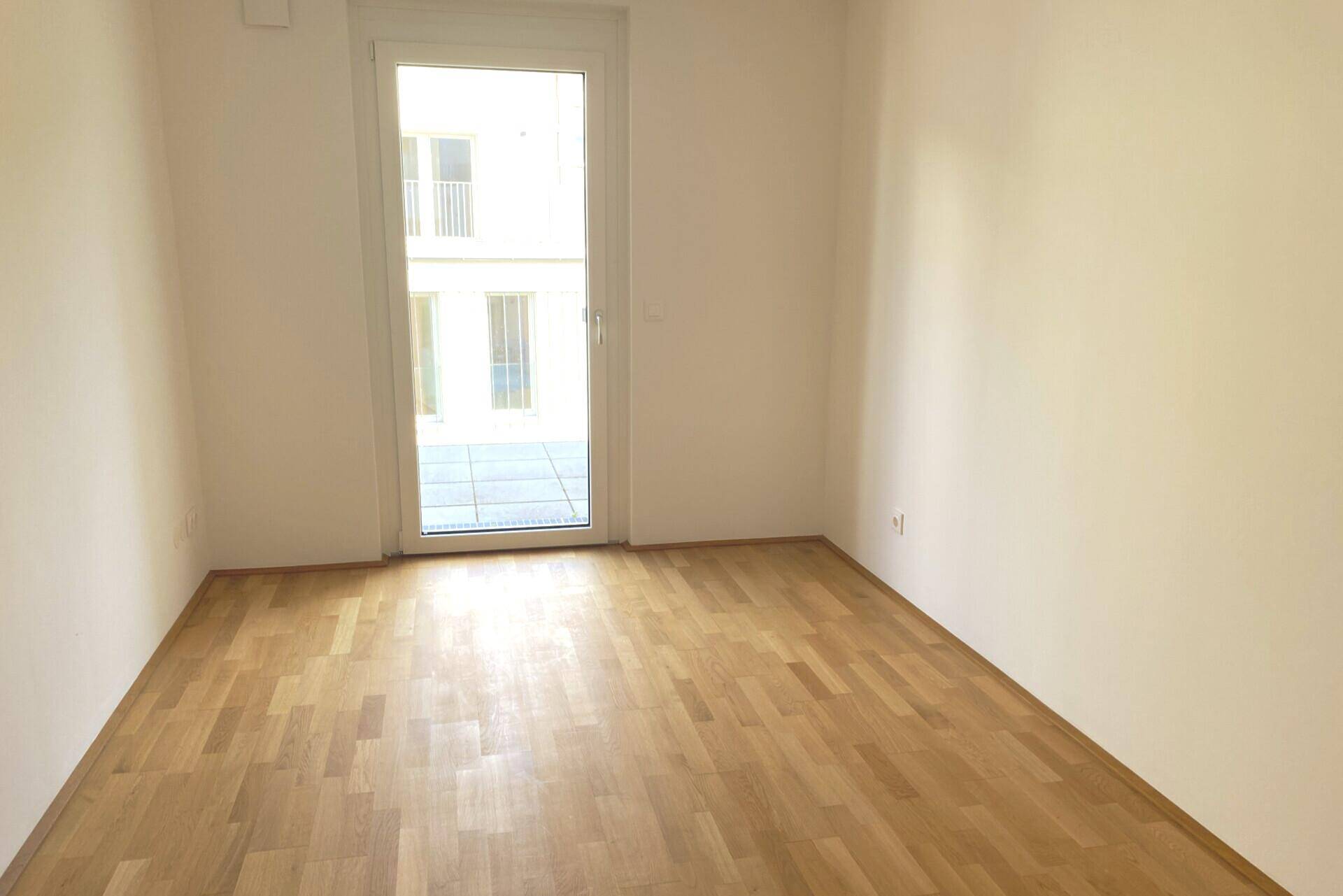 Ruhiges Zimmer mit Parkettboden und Balkontür, ideal als Schlaf- oder Arbeitszimmer.