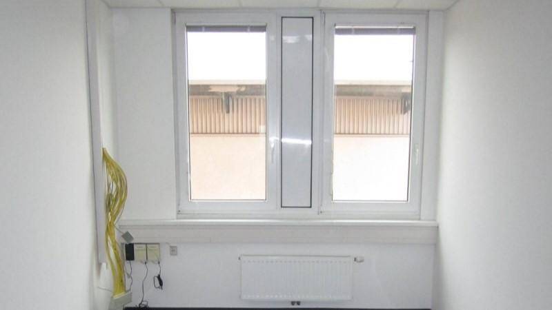 Kleiner Büroraum mit einem Fenster, weiß gestrichenen Wänden und einem Heizkörper.