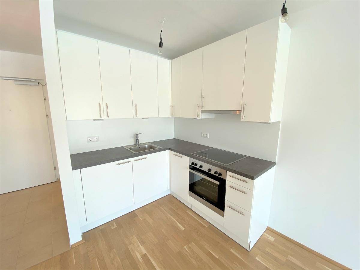 Moderne Einbauküche mit weißen Schränken, grauer Arbeitsplatte und Induktionskochfeld.
