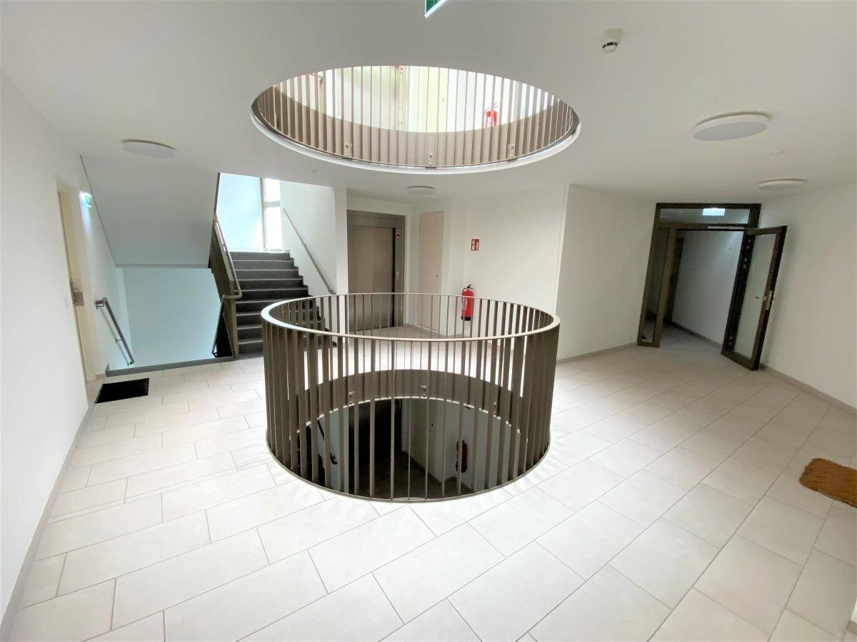 Heller Eingangsbereich mit modernem Design, Treppenhaus und Aufzug im Gebäude.