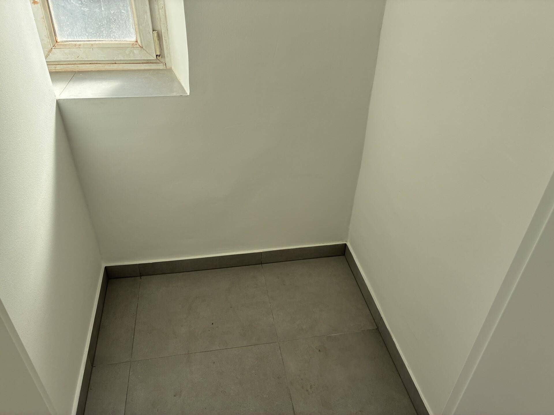 Kleiner, gefliester Raum mit einem Fenster, ideal als Abstellraum oder Nische nutzbar.