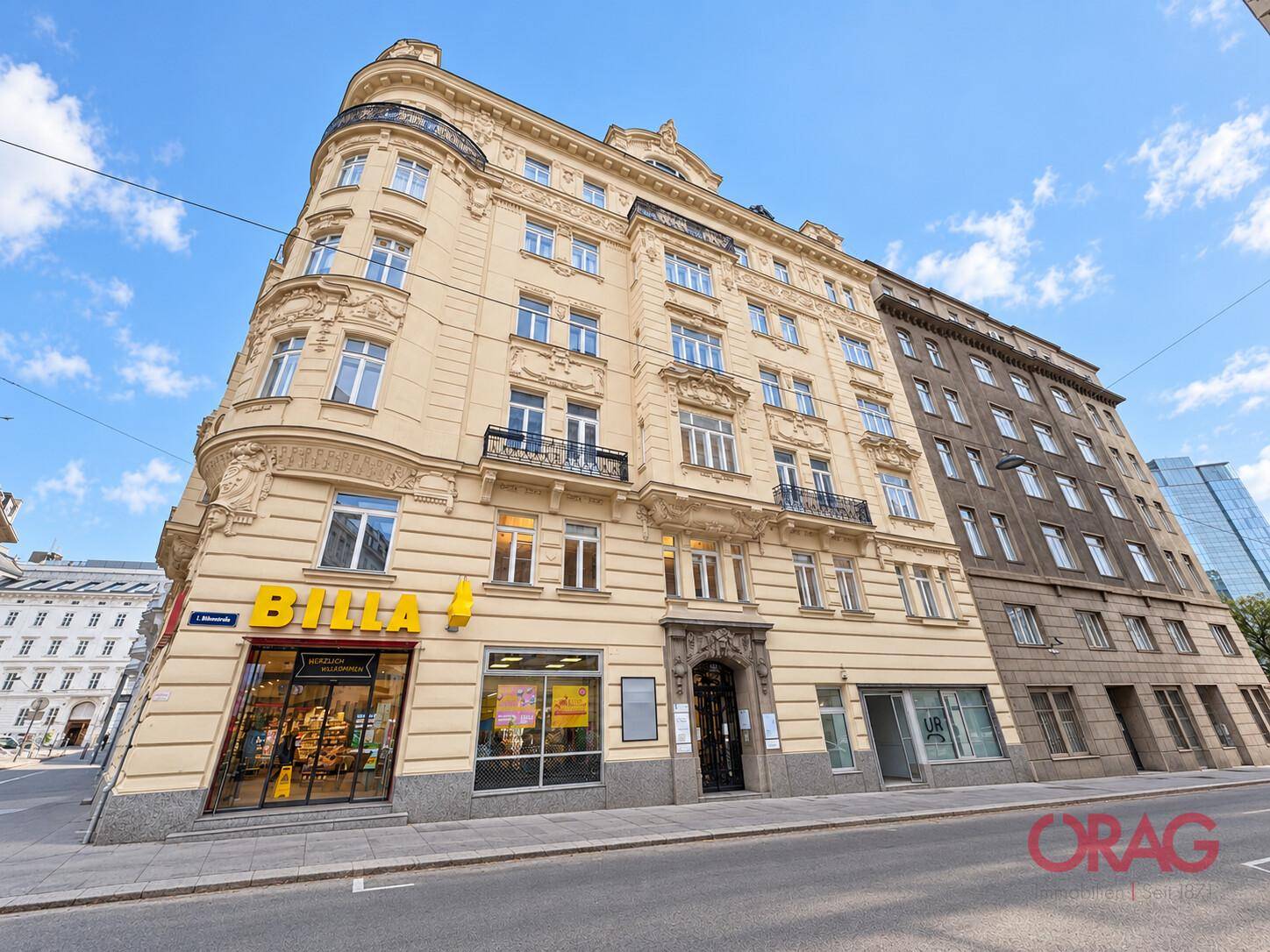 Historisches Eckgebäude mit klassischer Fassade, Balkonen und einem Geschäft im Erdgeschoss.