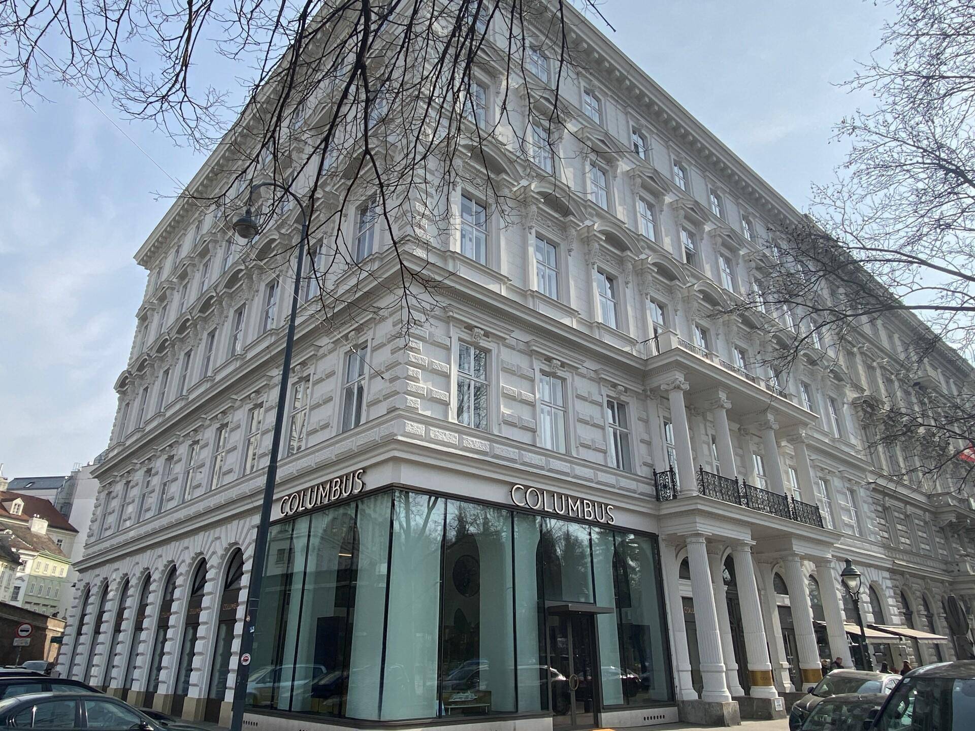 Historisches Gebäude mit klassischer Architektur, vielen Fenstern und einem Geschäft im Erdgeschoss.