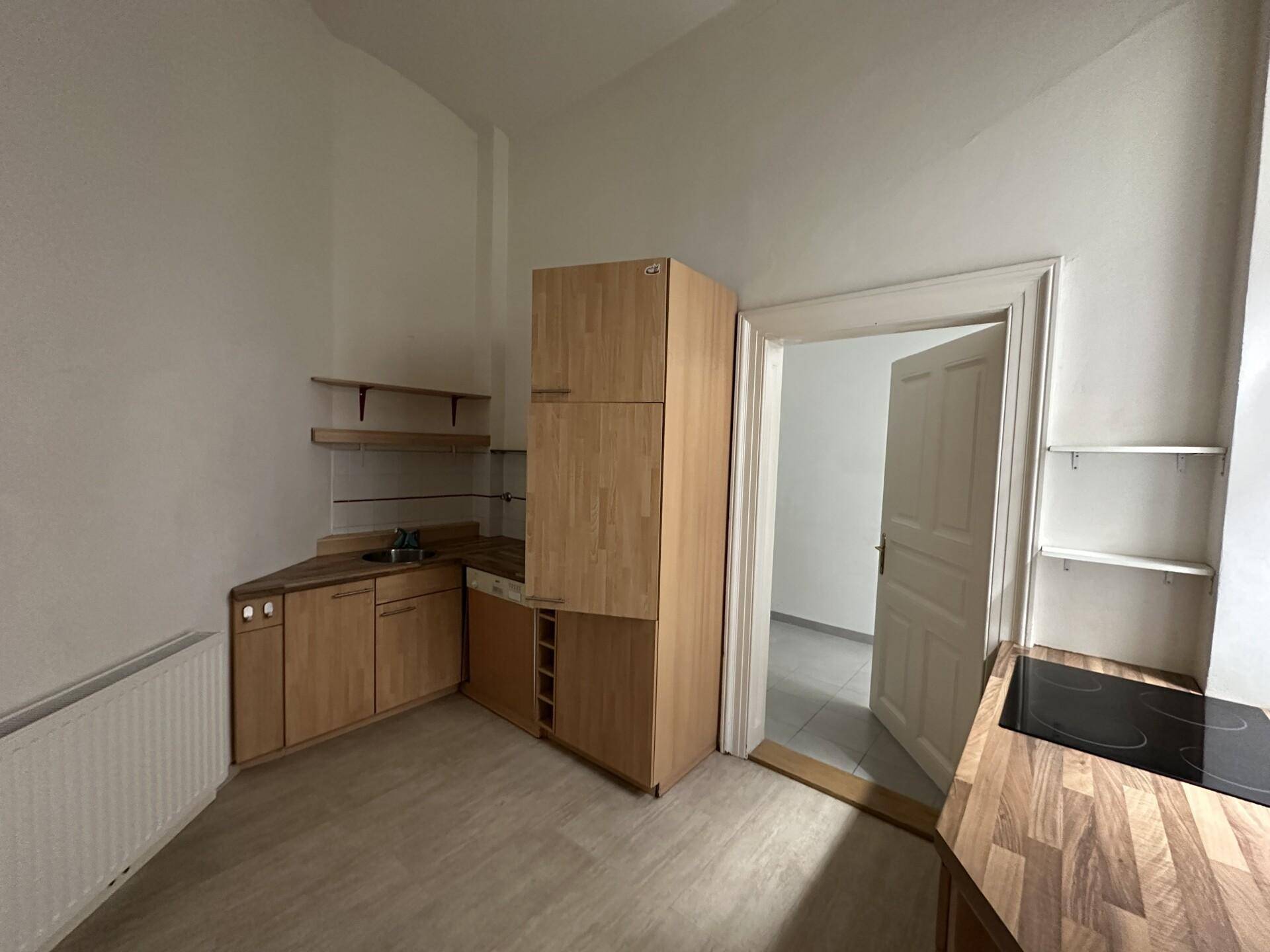 Kleine Küche mit Holzschränken, Spüle und Kochfeld, ideal für kompaktes Wohnen.