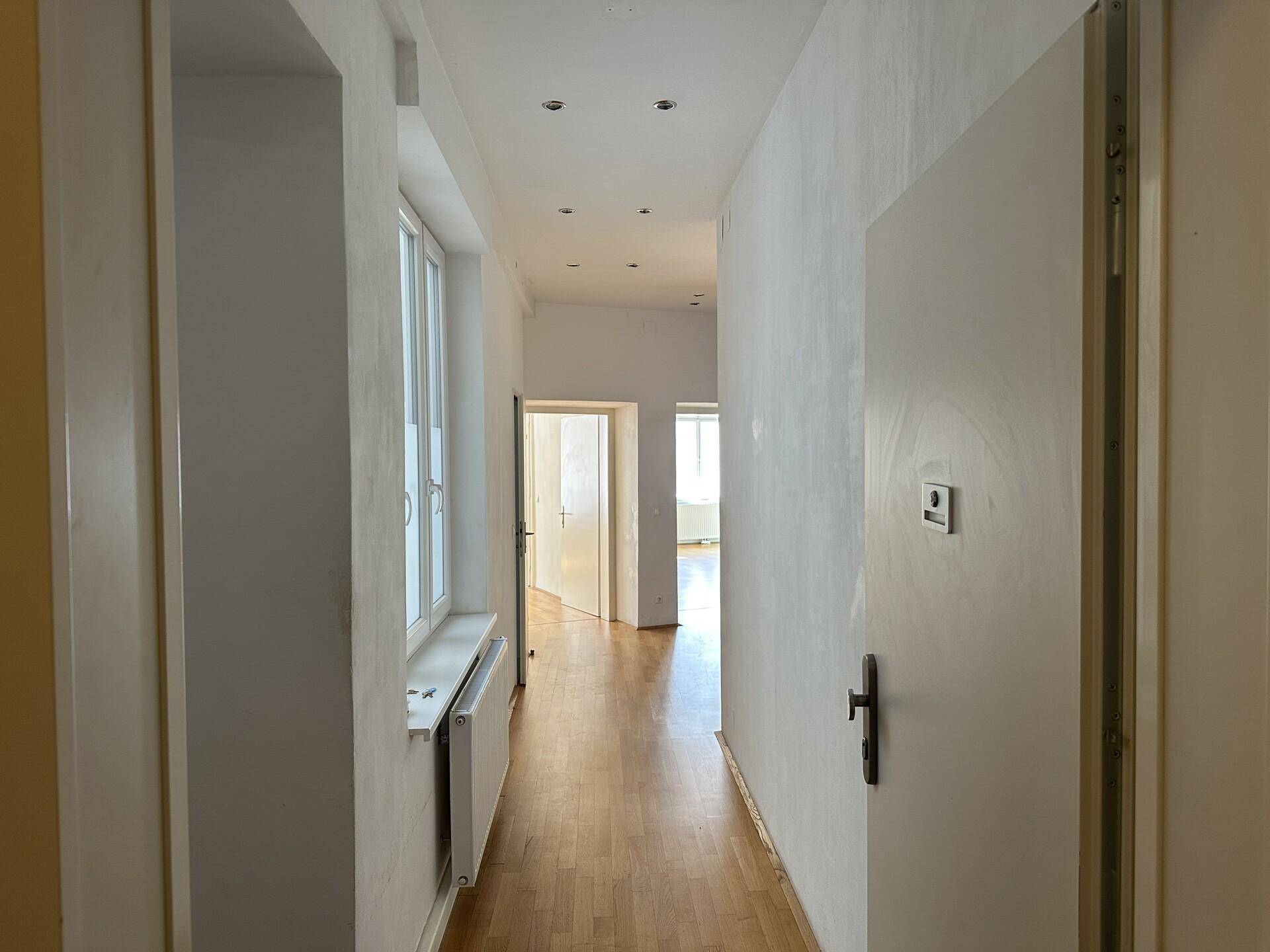 Langer Flur mit Parkettboden und mehreren Türen, der verschiedene Räume der Wohnung verbindet.