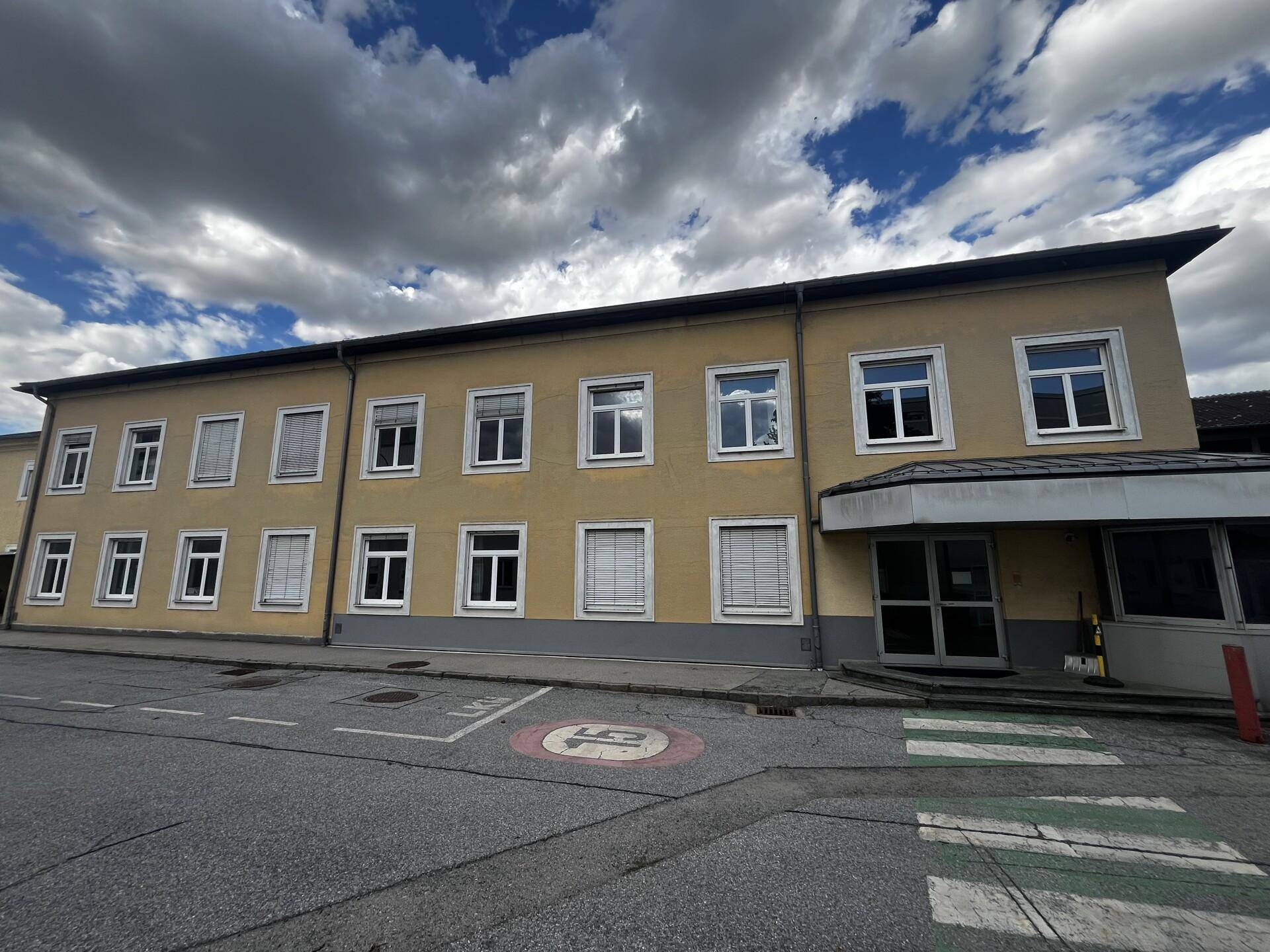 Mehrstöckiges Geschäftsgebäude mit gelber Fassade und zahlreichen Fenstern an einer Straße.