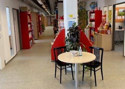 Heller Gemeinschaftsbereich mit Bücherregalen, einem kleinen Tisch und Stühlen, ideal für Pausen.