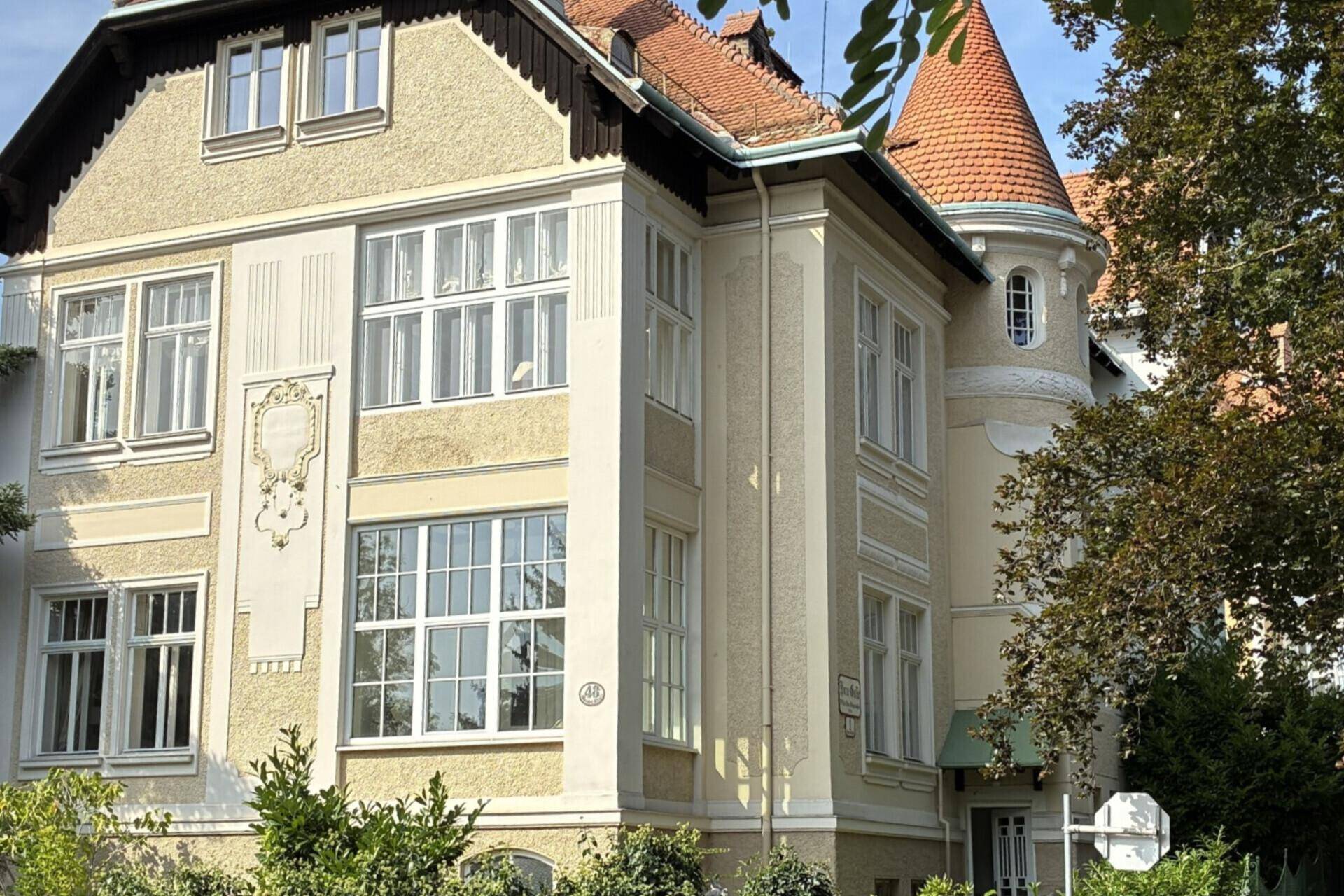 Detailansicht der historischen Villa mit kunstvollen Verzierungen und großen Fenstern.