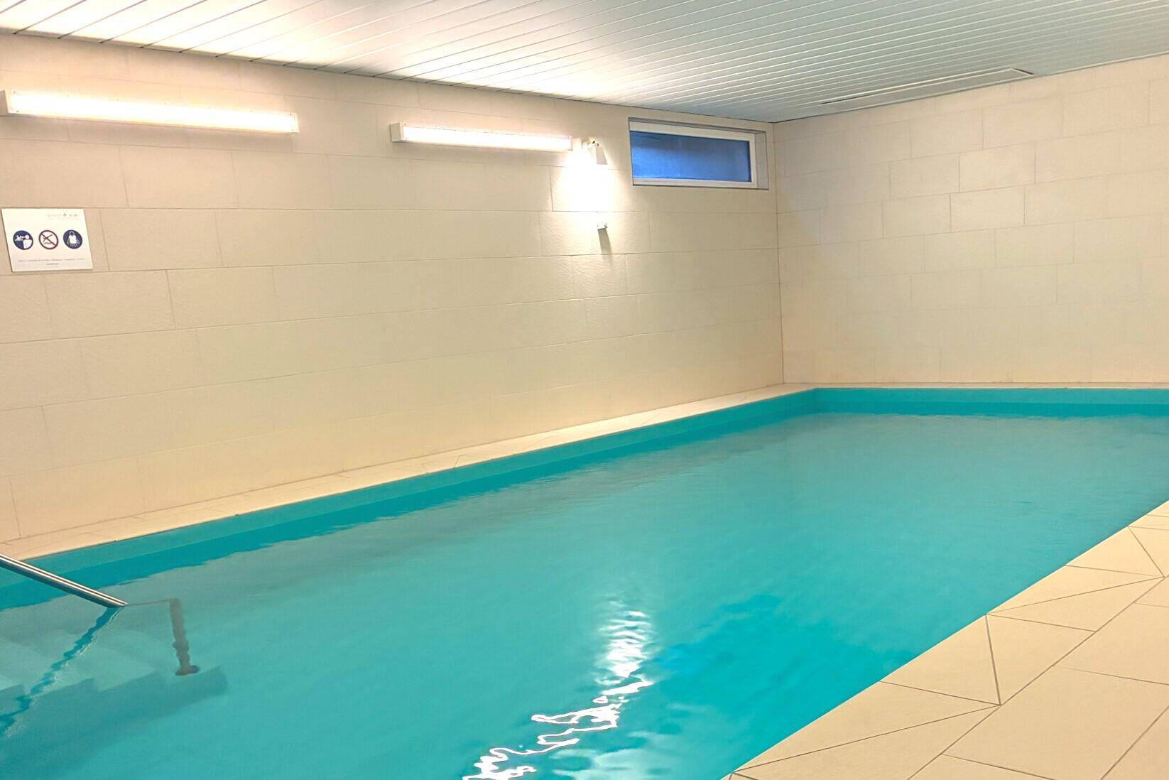 Innenpool in einem Wellnessbereich mit hellen Fliesen und indirekter Beleuchtung.