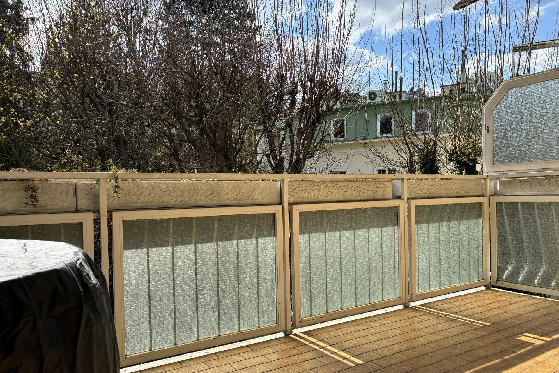 Balkon mit Holzboden und blickdichter Brüstung, umgeben von Bäumen und Natur.