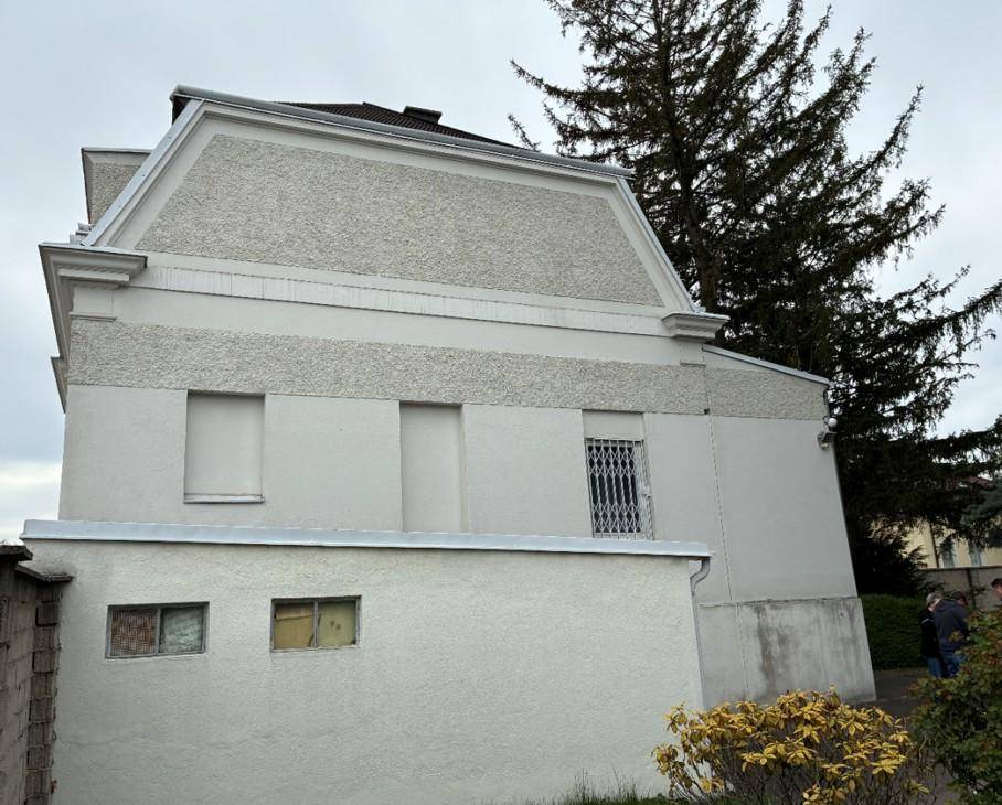 Seitenansicht des Gebäudes mit schlichten Fenstern und einer schützenden Gitterstruktur.