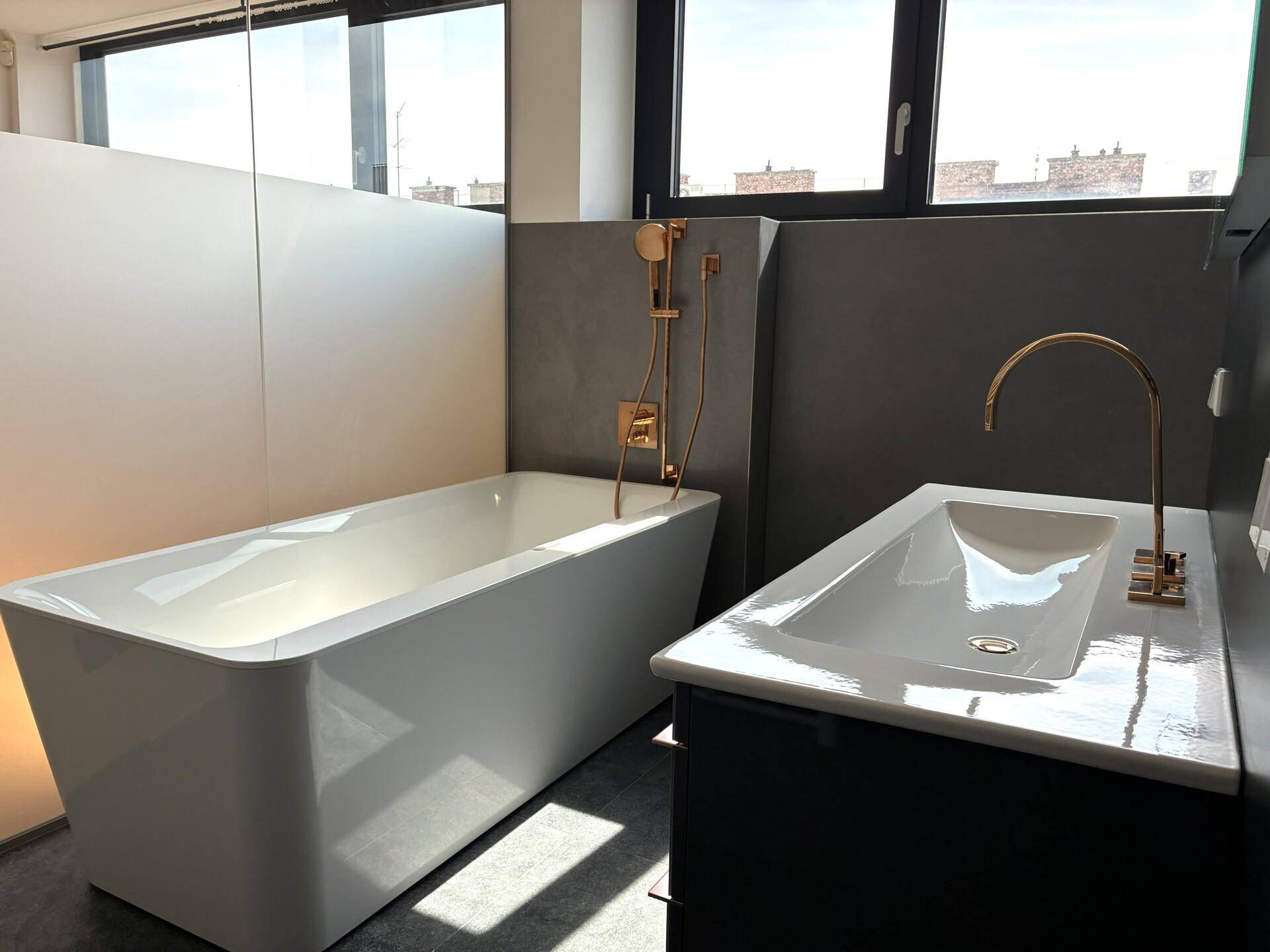 Modernes Badezimmer mit freistehender Badewanne, Einzelwaschbecken und goldenen Armaturen.