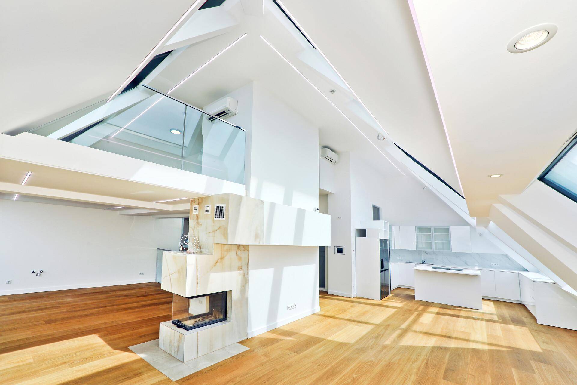 Heller, offener Wohnbereich mit Kamin, Holzboden und Galerie mit Glasgeländer.