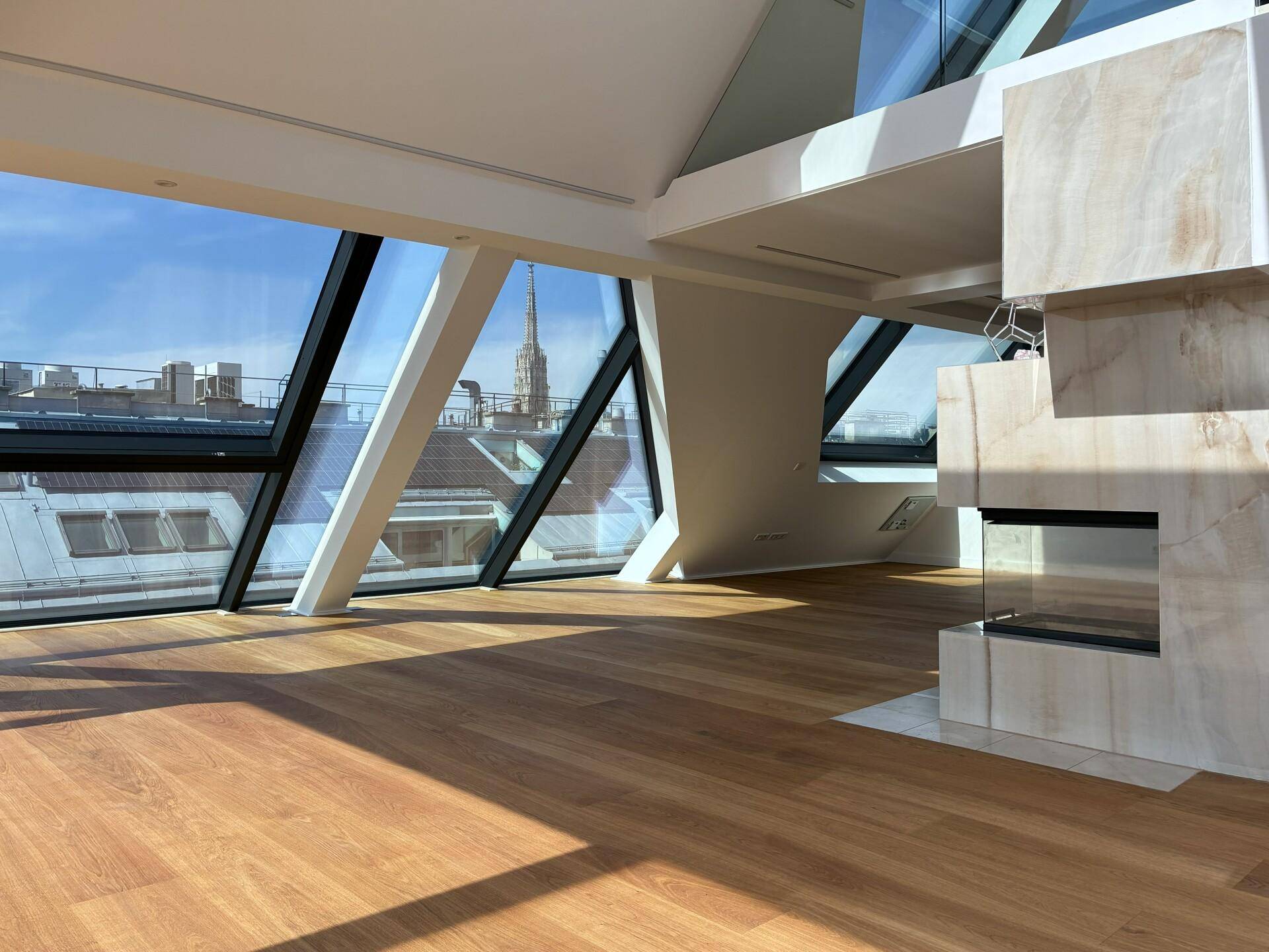 Moderner Wohnraum mit Holzboden, Kamin und weitem Blick über die Dächer der Stadt.