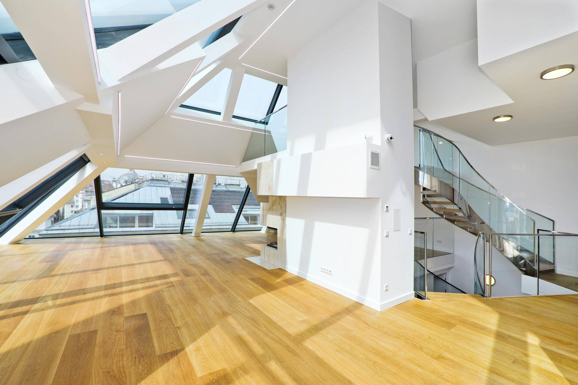 Geräumiger Wohnbereich mit Holzboden, Kamin und offener Galerie mit Glasgeländer.