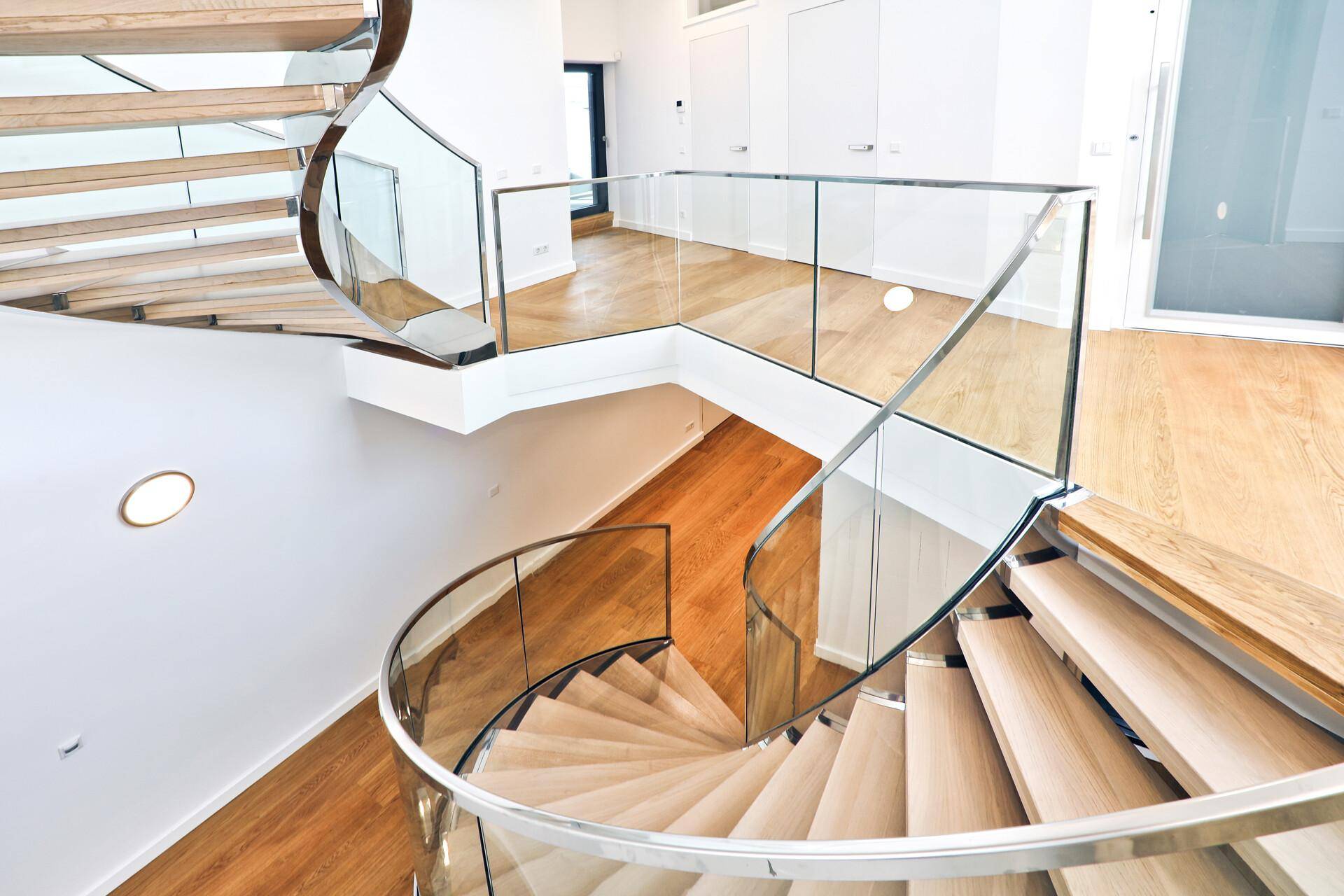 Elegante Wendeltreppe aus Holz und Glas, die verschiedene Ebenen des Penthouses verbindet.