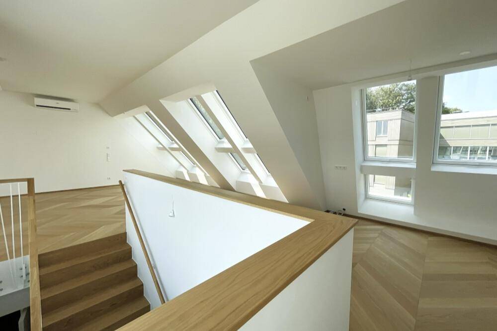 Moderner Treppenaufgang mit Holzstufen und Geländer in einem hellen Wohnbereich.