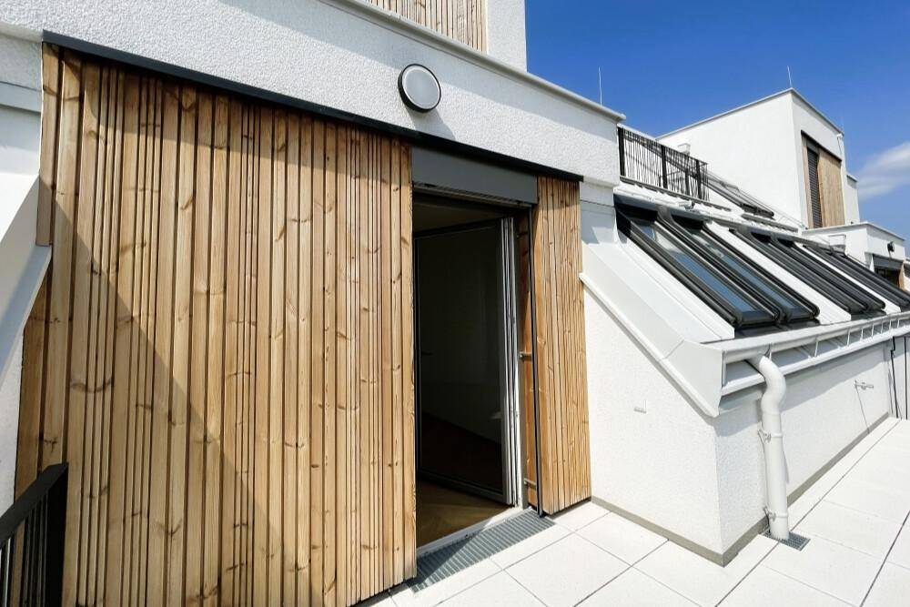 Eingangsbereich zur Wohnung von der Terrasse aus mit Holzverkleidung und Dachfenstern.