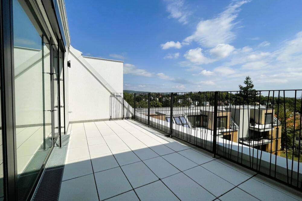 Helle Terrasse mit modernem Geländer und Panoramablick unter blauem Himmel.