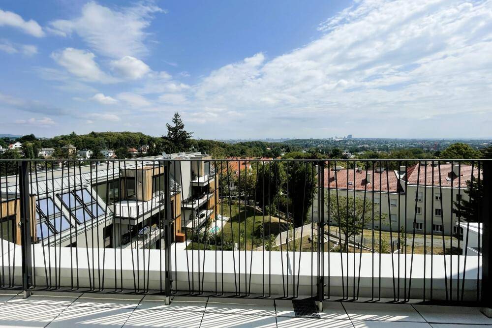 Weitläufiger Ausblick von der Terrasse über die grüne Umgebung und die Stadtlandschaft.