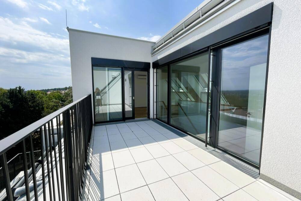 Moderne Dachterrasse mit Fliesenboden und Zugang zu den Innenräumen der Wohnung.