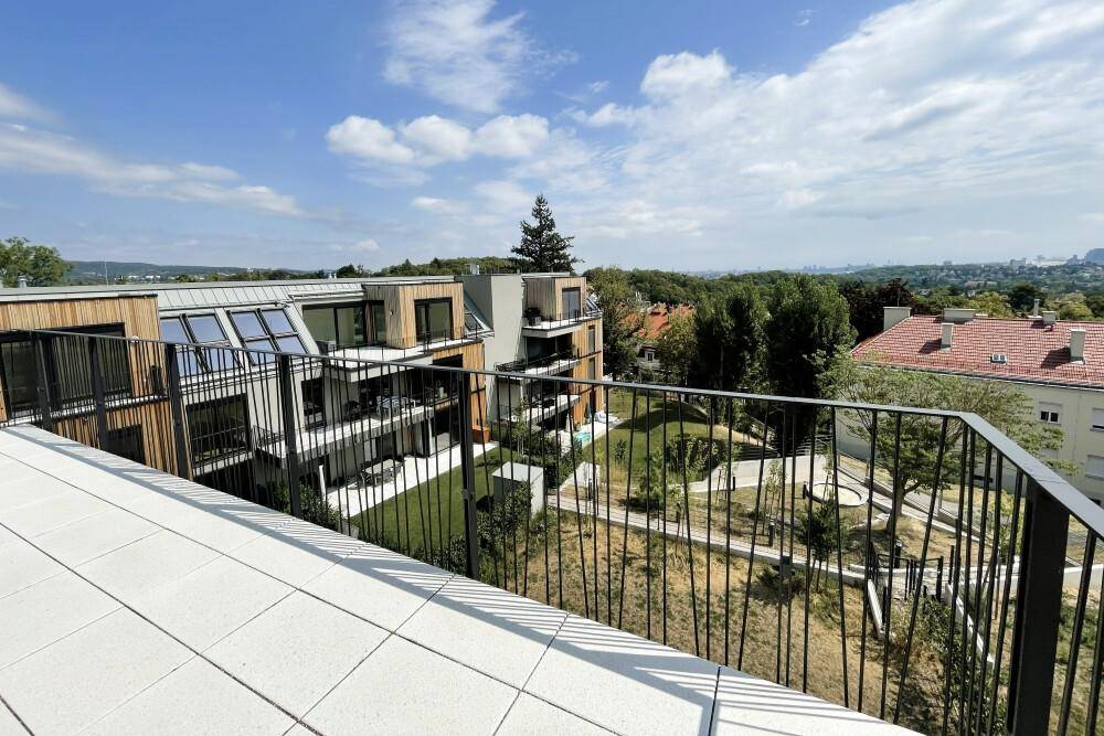 Aussicht von der Terrasse auf die moderne Wohnanlage und die umliegende Natur.