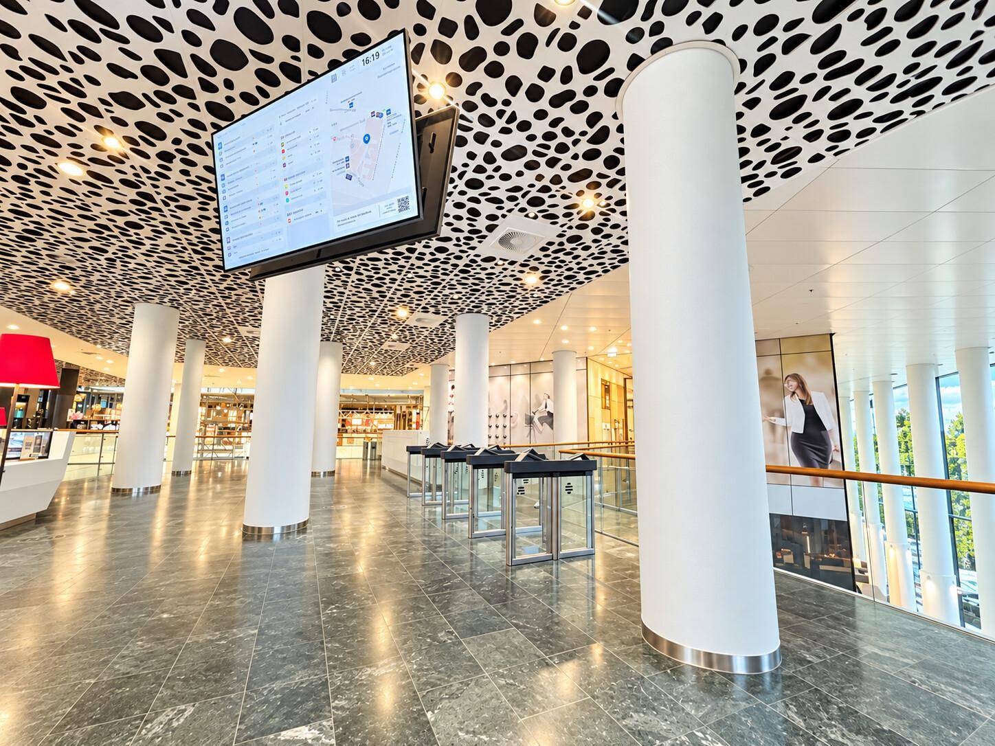 Geräumige Eingangshalle mit modernem Design, gemustertem Deckenpanel und Zugangskontrollsystem.