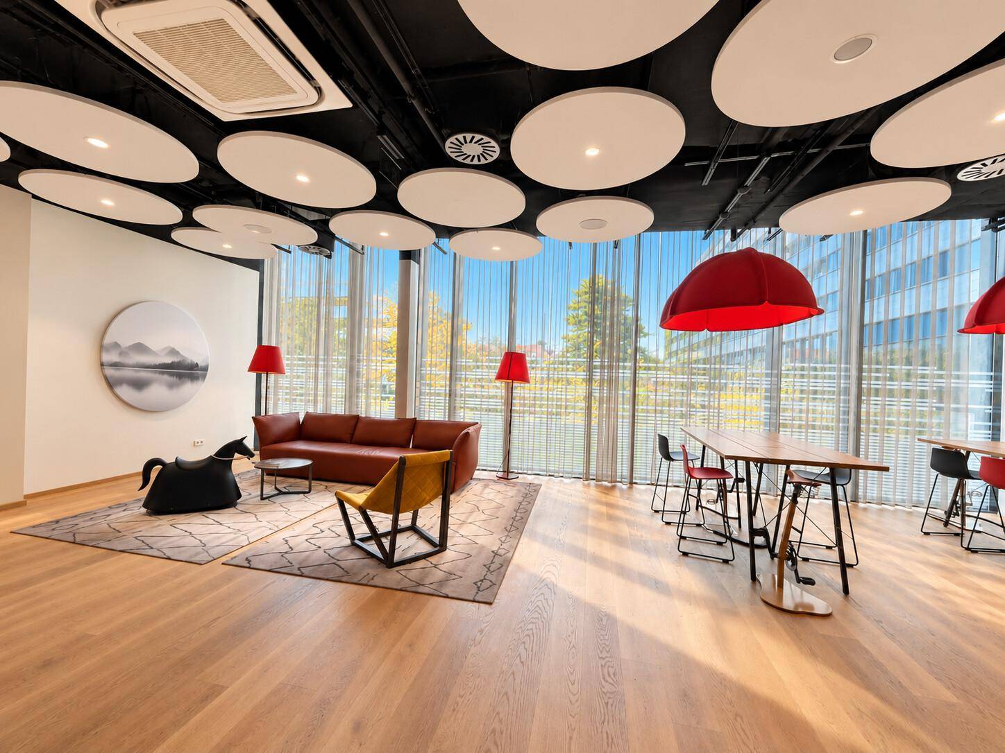 Gemütlicher Lounge-Bereich mit bequemen Sofas, Holzboden und dekorativen Deckenpaneelen.